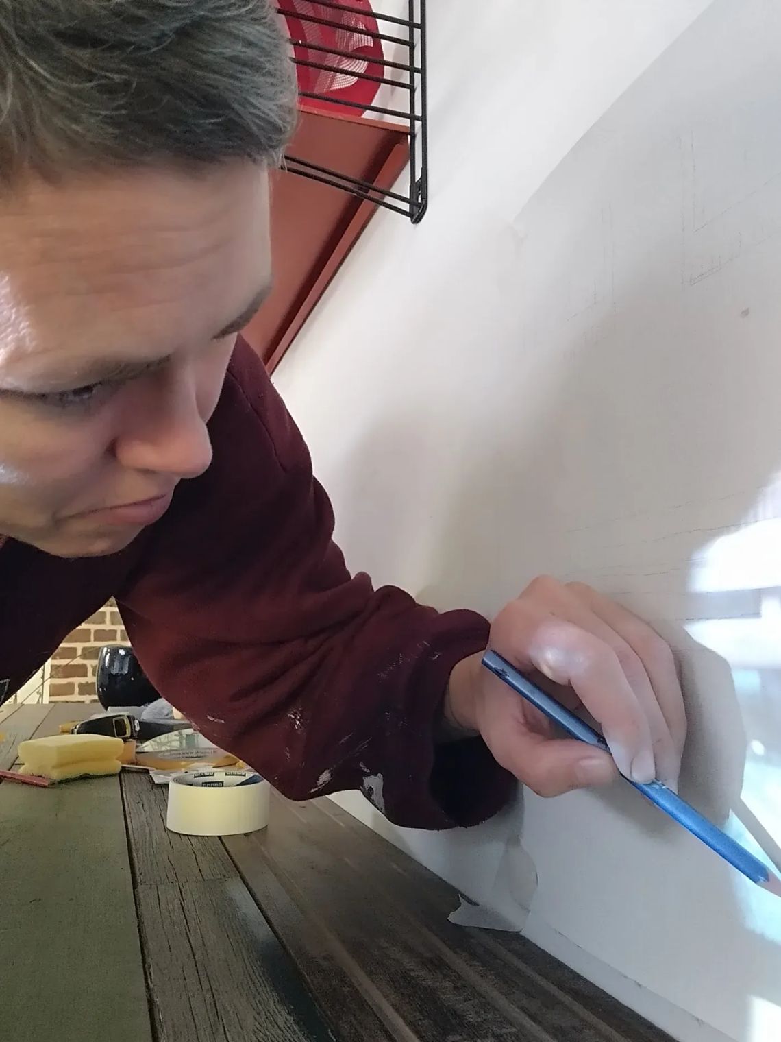Ellen Claes painting a wall surface with a blue brush, showing her focus and slow, meditative process from the series Can Painting Slow You Down in a Fast World? Image courtesy of the artist.