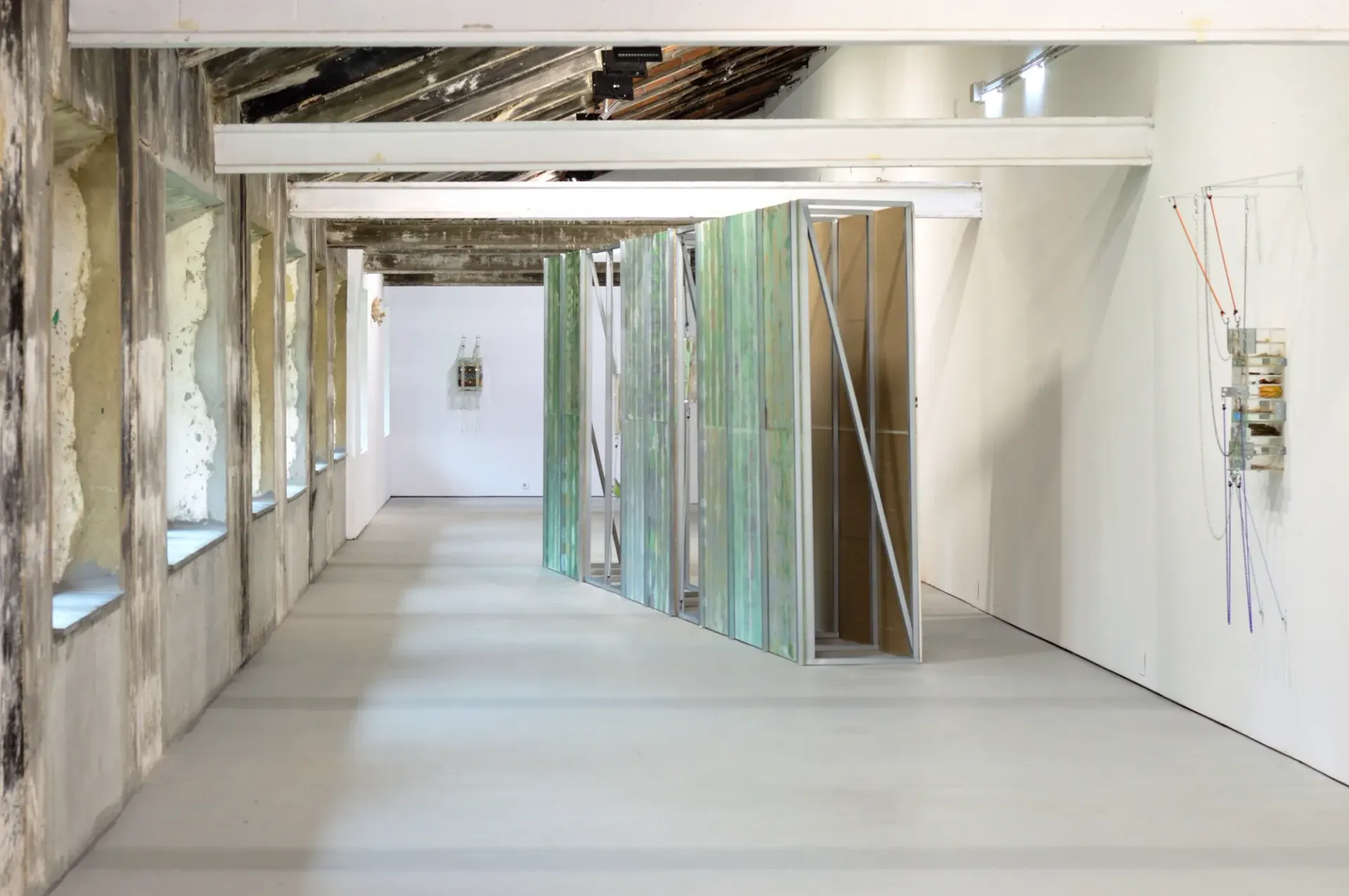 Exhibition review of Gabriel Alonso: A Long Chemical Dream at ATM Galería, Gijón, 2026. Long hall with exposed beams and a freestanding green printed wall.