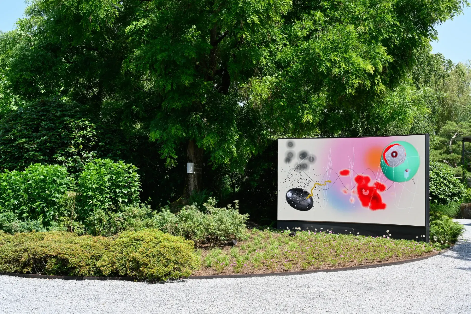 Artist Profile Feature: KiefferWoodtli, Arboreal Serenade, 2025. A wide screen with painted abstract forms beside a tree in a garden.