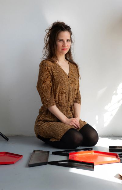 Céline Struger artist portrait sitting in studio with ceramic and steel sculptural elements on the floor, photographed by Robert Gruber