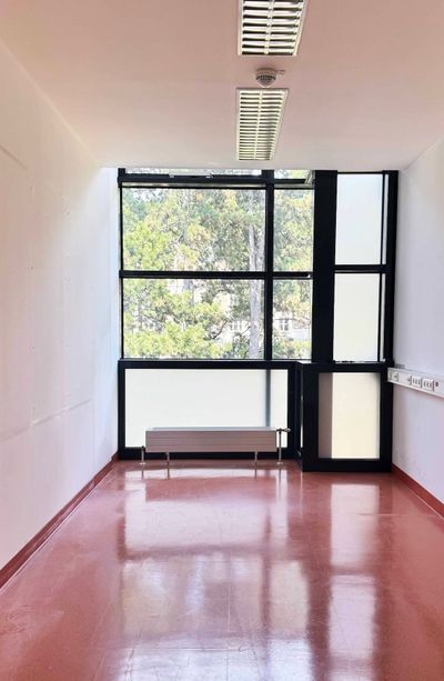 Parallel vienna 2026 art fair - Empty exhibition room with tall black steel-framed windows overlooking trees and a glossy terracotta floor at the Otto Wagner Areal, Vienna.