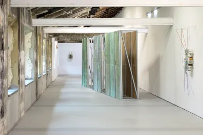 Exhibition review of Gabriel Alonso: A Long Chemical Dream at ATM Galería, Gijón, 2026. Long hall with exposed beams and a freestanding green printed wall.