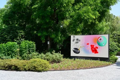 Artist Profile Feature: KiefferWoodtli, Arboreal Serenade, 2025. A wide screen with painted abstract forms beside a tree in a garden.