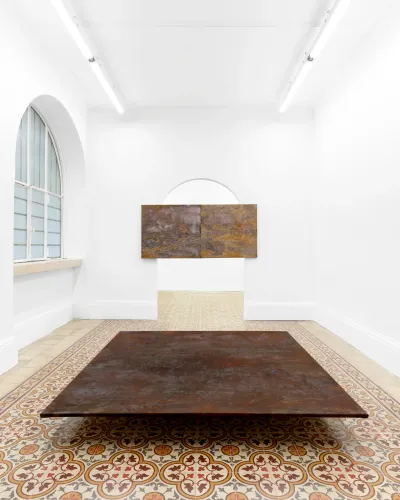 Taylah Hasaballah, INDICATRIX at The Address, Brescia, 2026. Rust-brown floor work with a two-panel painting behind.
