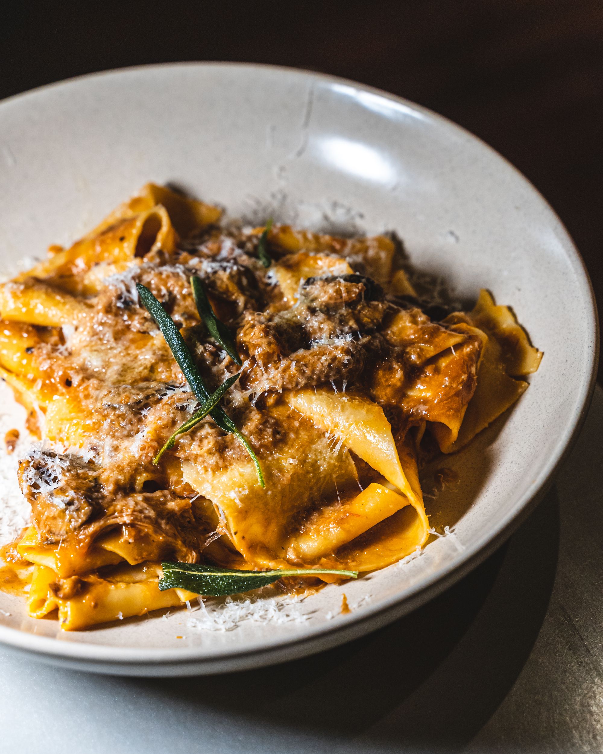 Close up of pappardelle pasta with pieces of braised duck