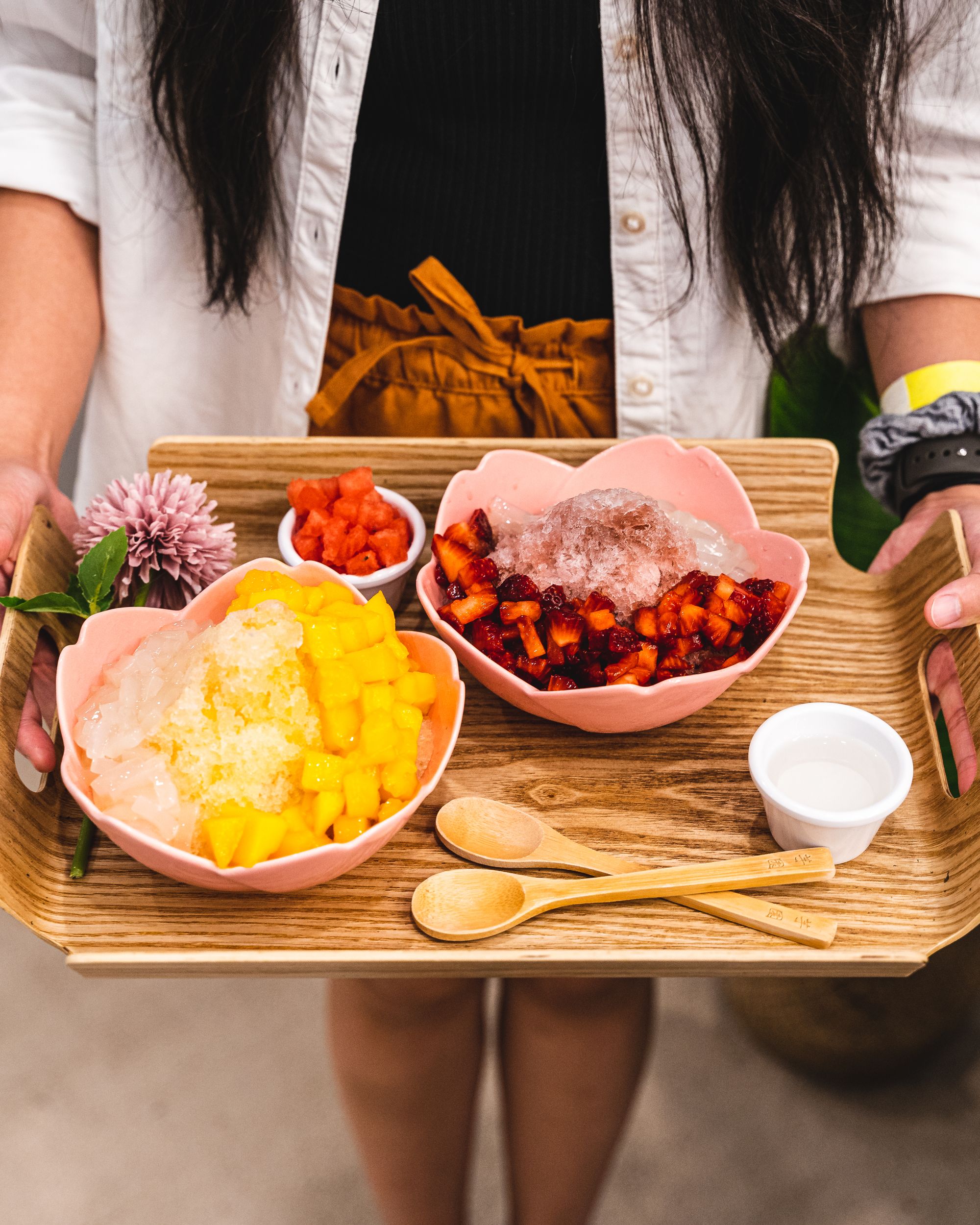 Side view of a tray being held with two bowls of shaved ice dessert