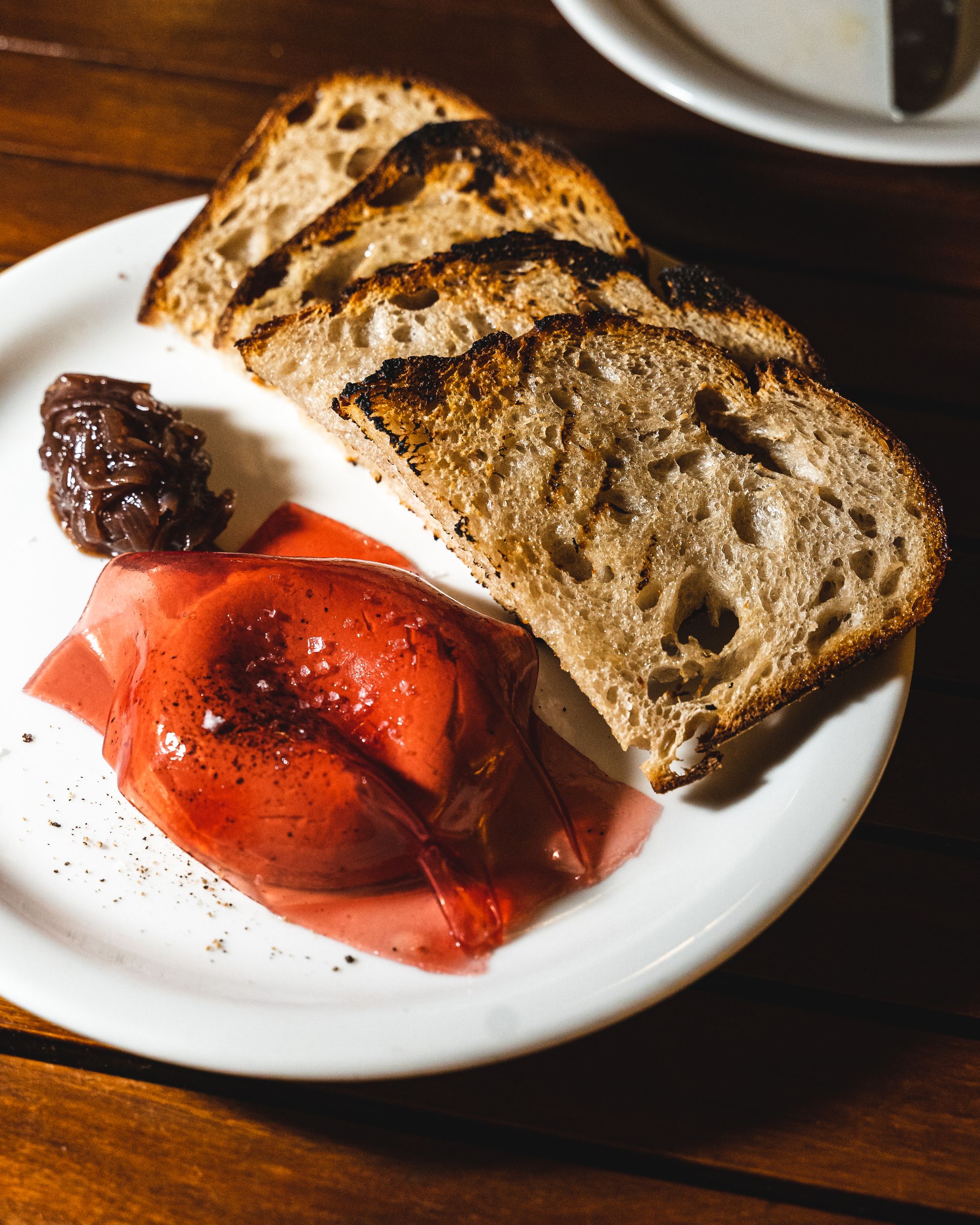 Close up of duck liver parfait with a film like sheet on-top of it and four slices of bread on the plate