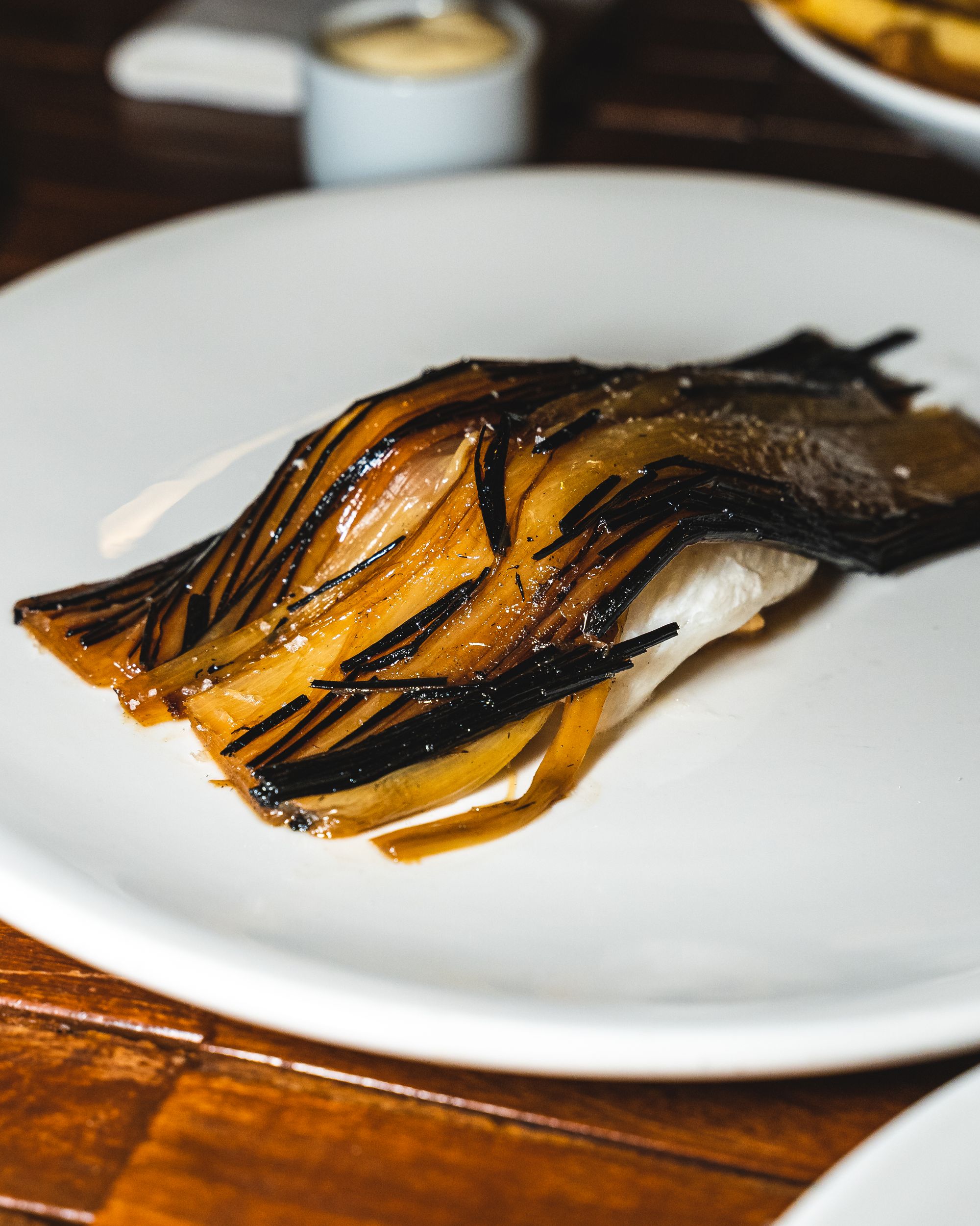 A piece of fish with a slice of leek layered on-top