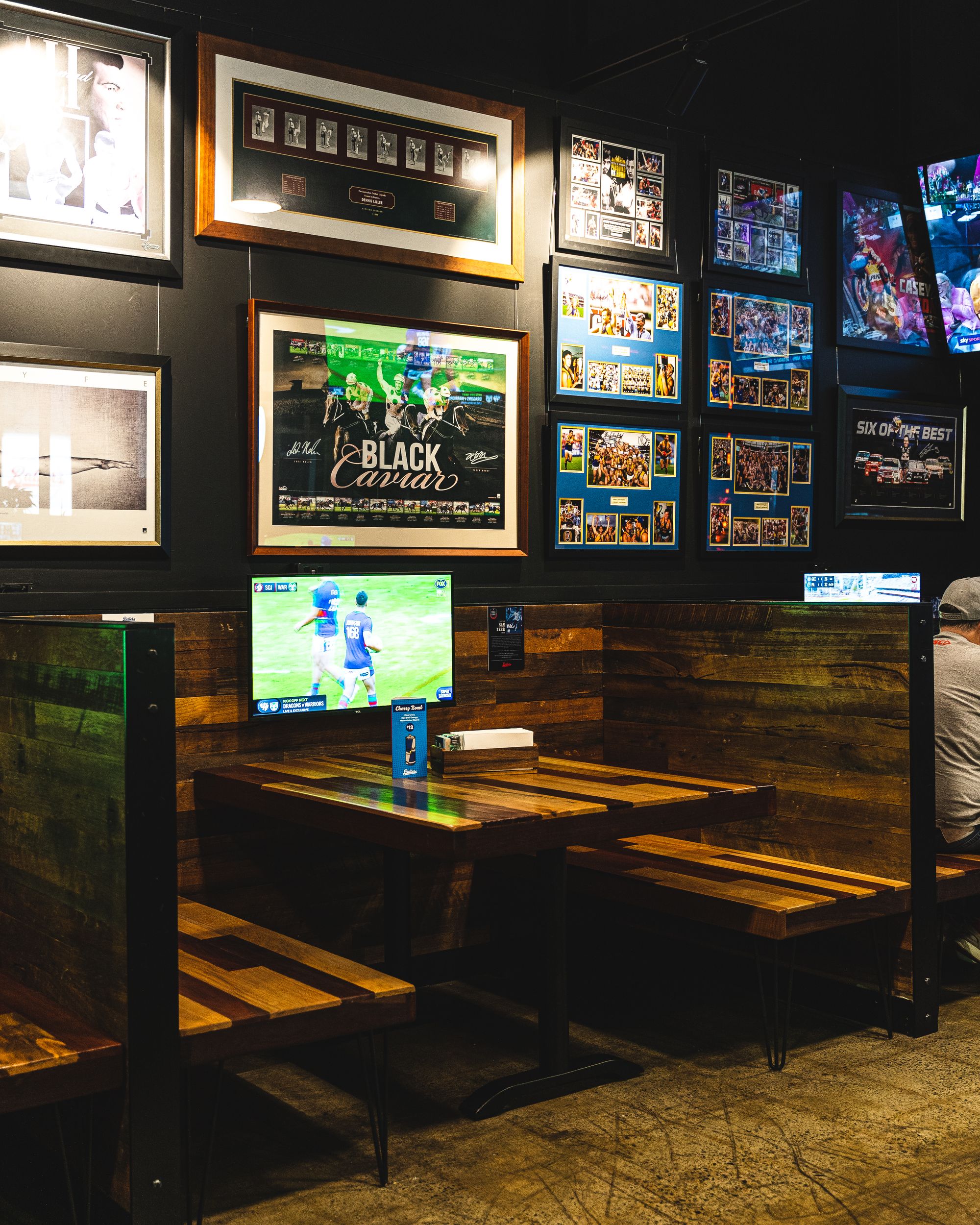 A semi-private booth with a TV, with a number of sports related paraphernalia hung up on the wall