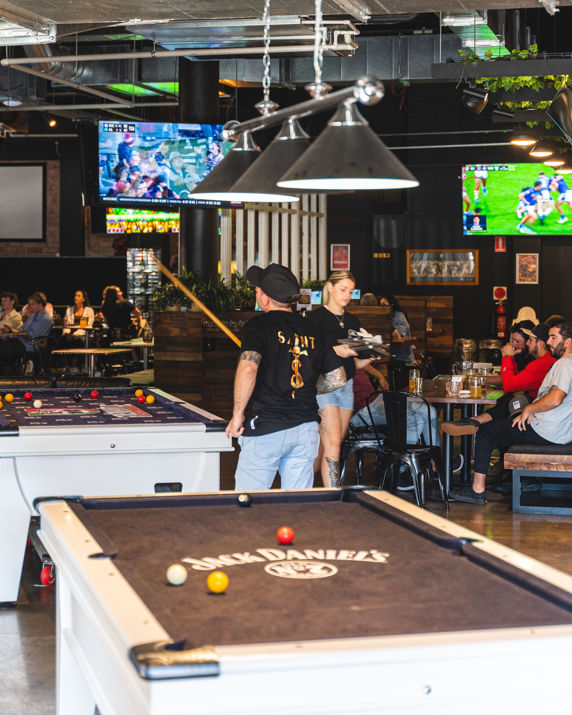 A man holding a pool cue in the middle of a bustling sports bar