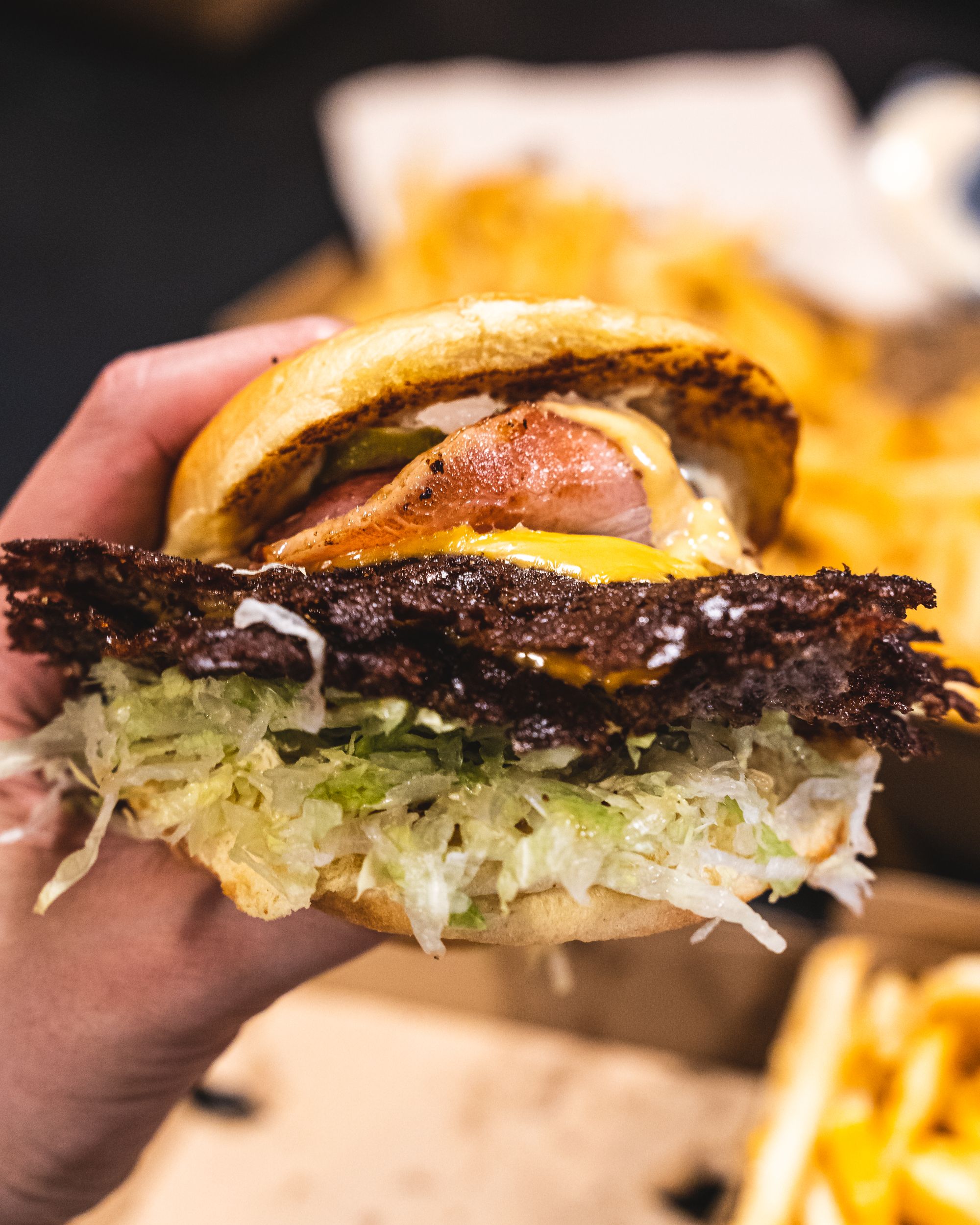 Close up of a smashed burger showing crispy beef patty edges, bacon and lettuce