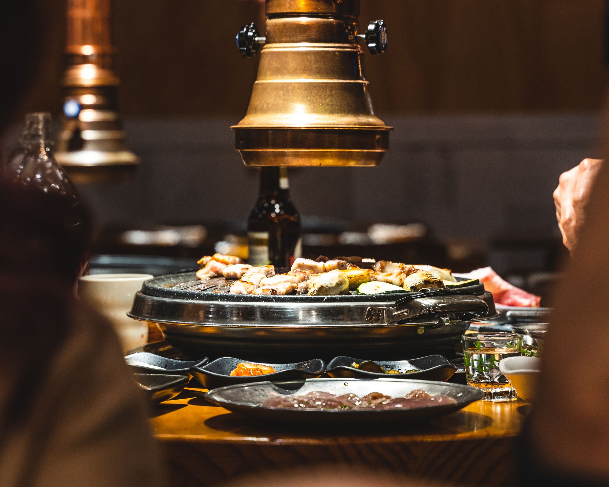 A Korean BBQ hot plate full with meat with the exhaust fan on-top