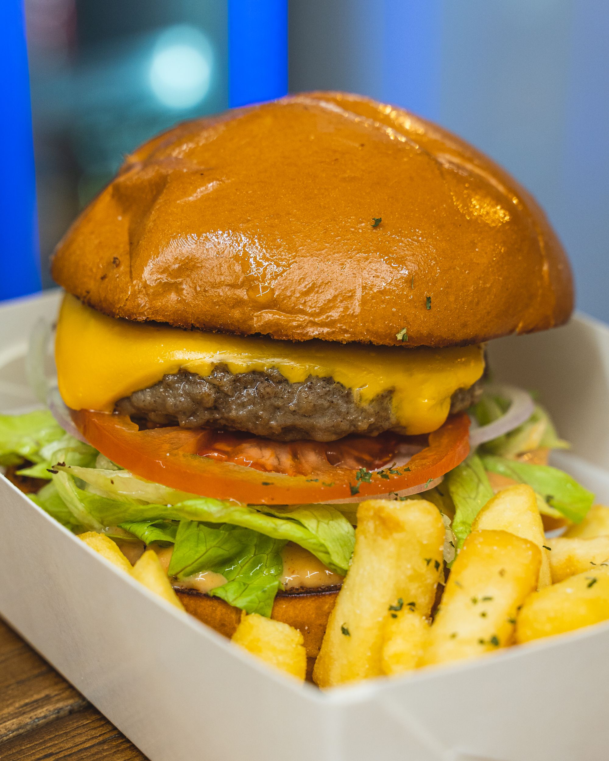Close up of beef burger with melted cheese, lettuce, tomato and fries