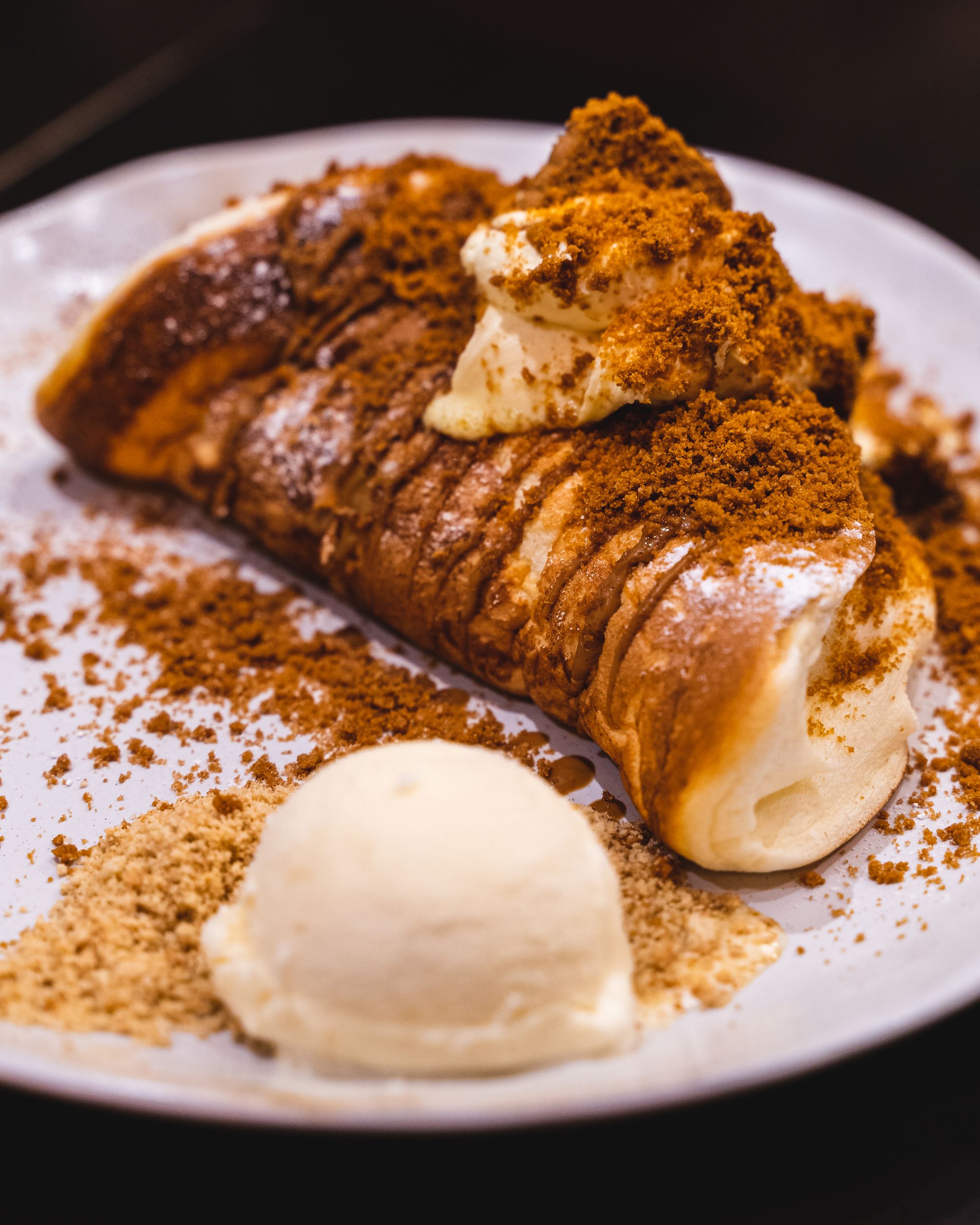 Close up of souffle pancake with biscoff crumbs and a side of ice-cream