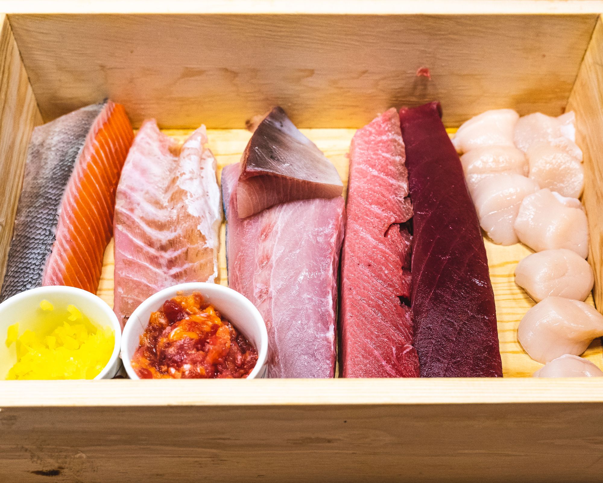 Wooden box with cuts of raw fish