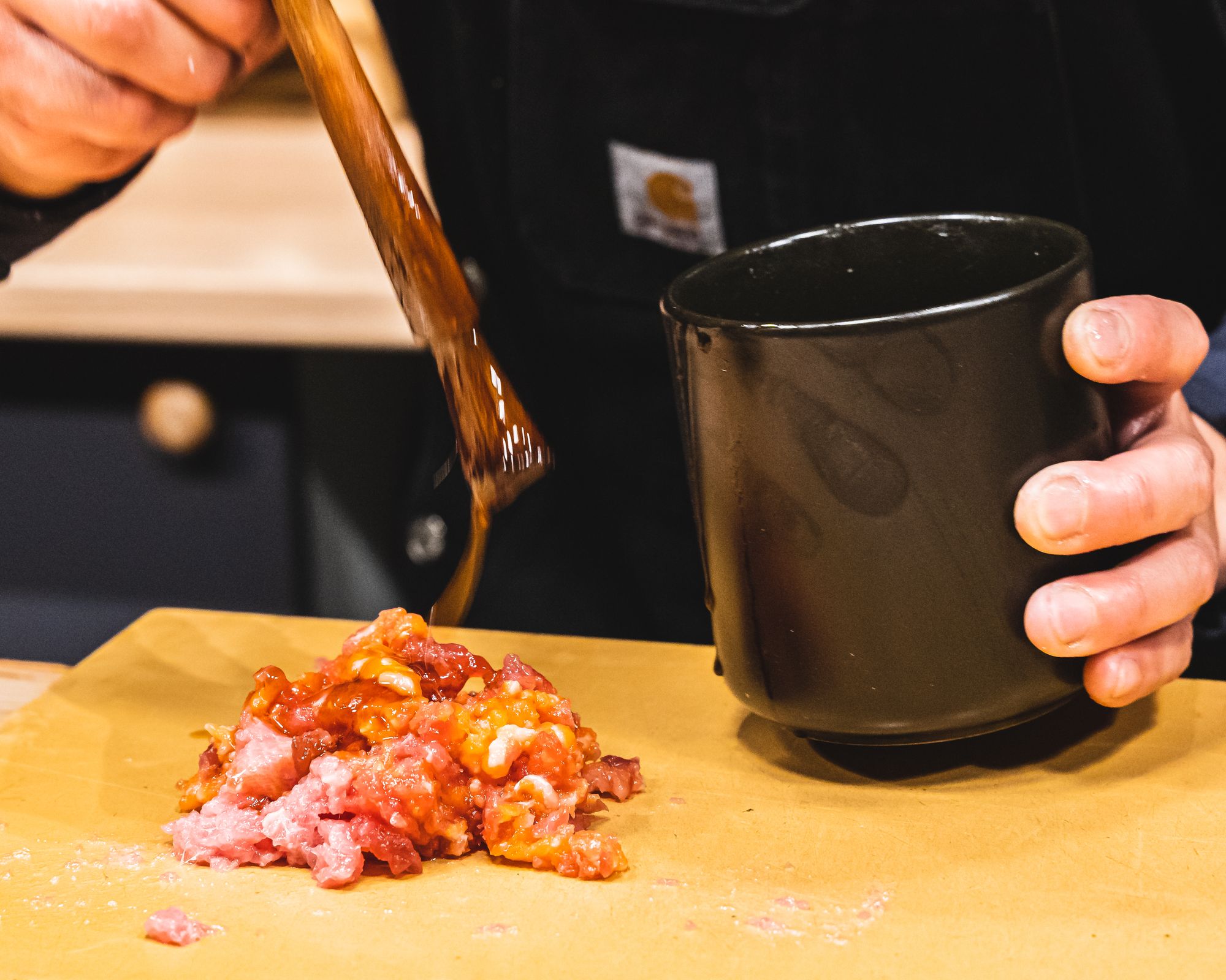 Tare (savoury sauce) being drizzled onto the tuna offcuts