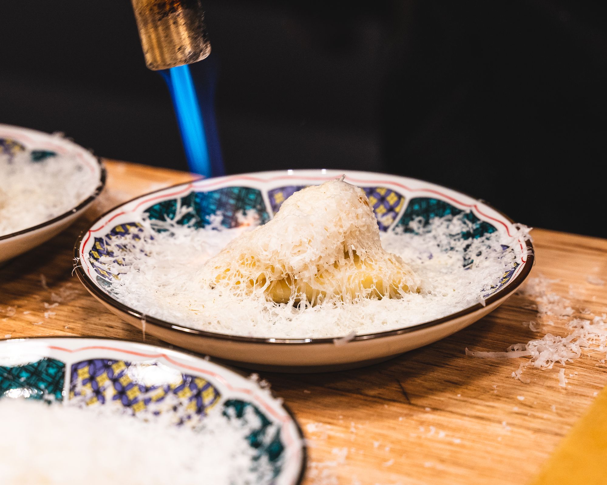 Blow torch searing cheese on black cod