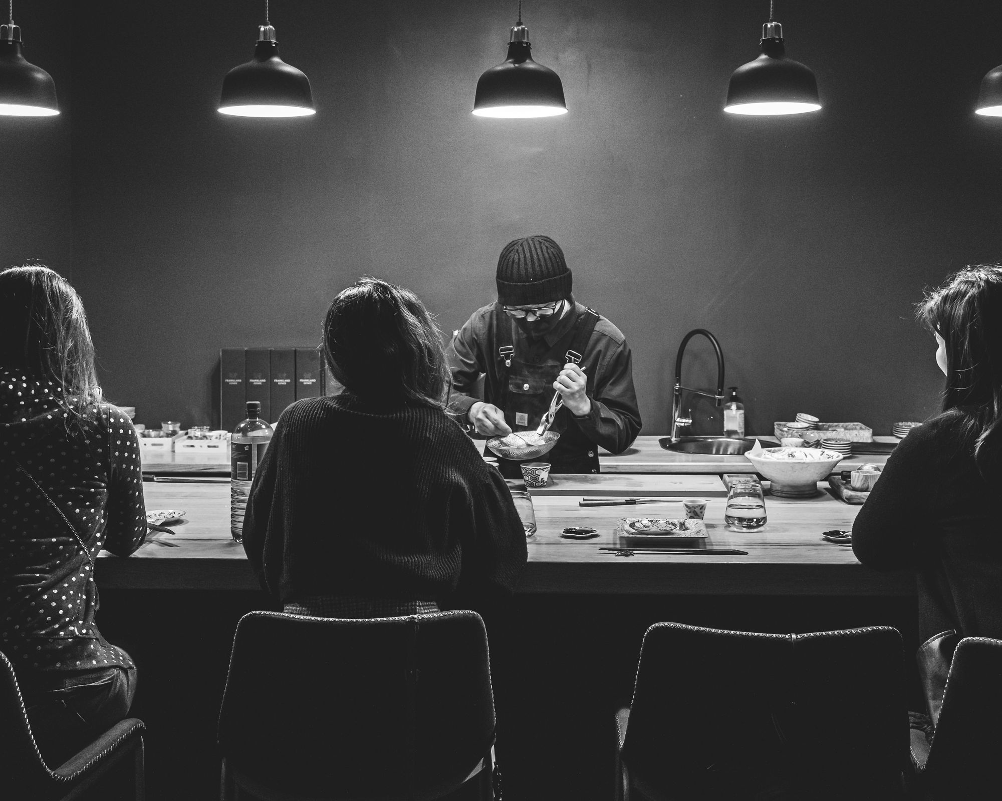 Black and white photo of chef cooking in-front of guests
