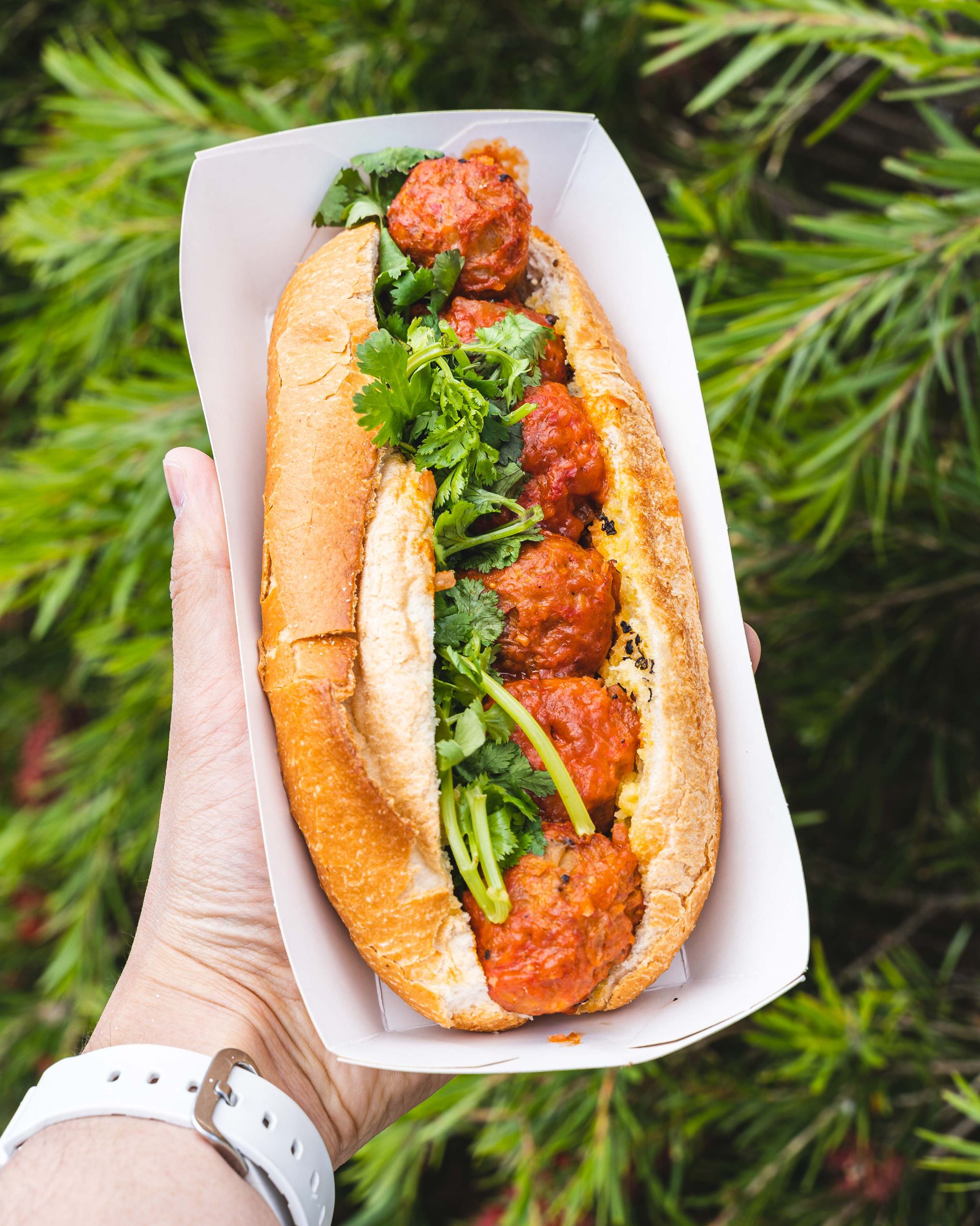 Hand holding pork meatball banh mi