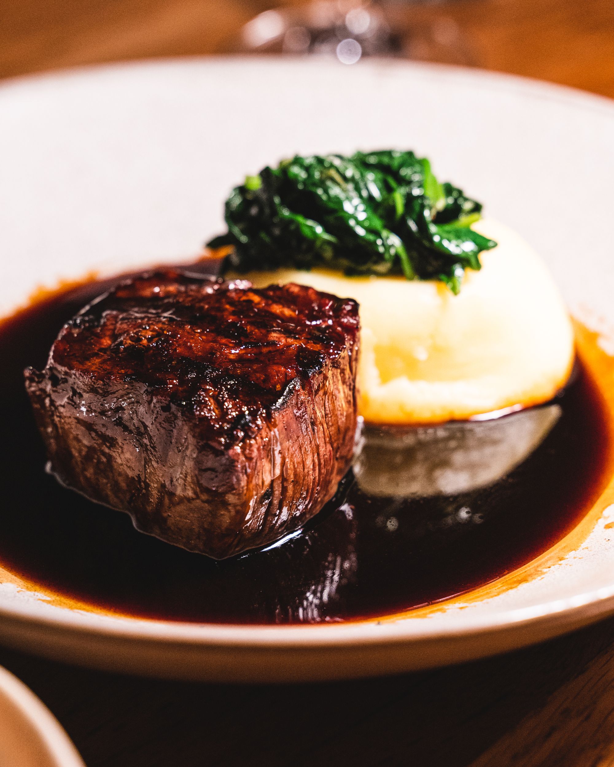 Steak on-top of jus and potato puree and spinach