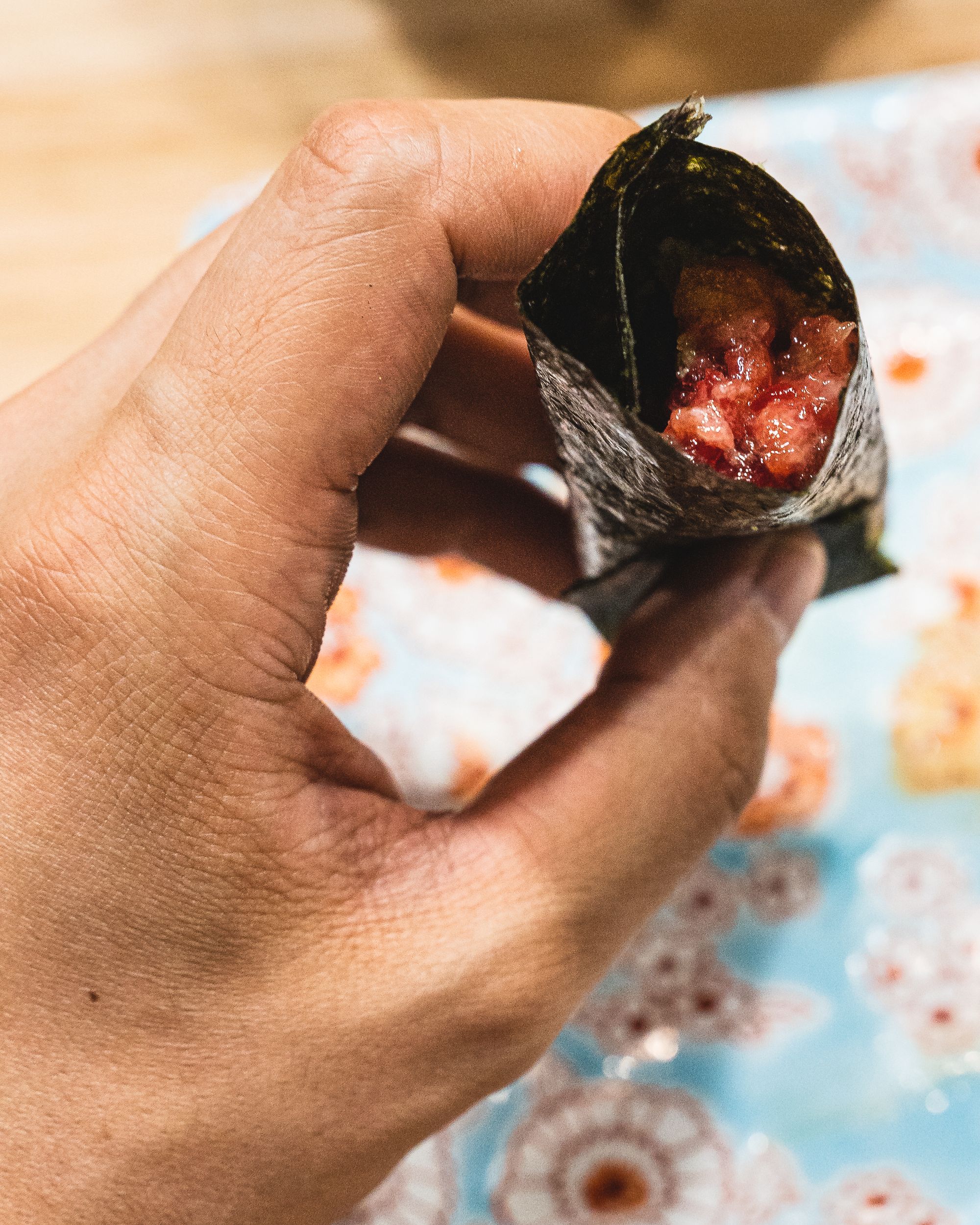 Hand holding a negi toro tuna roll
