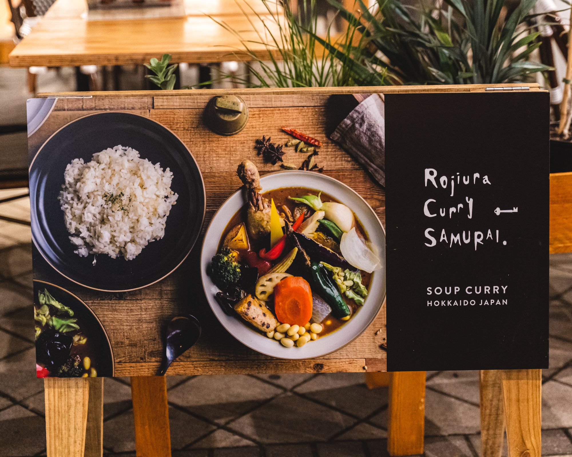 Sign saying "Rojiura Curry Samurai" with a photo of curry and rice on the side