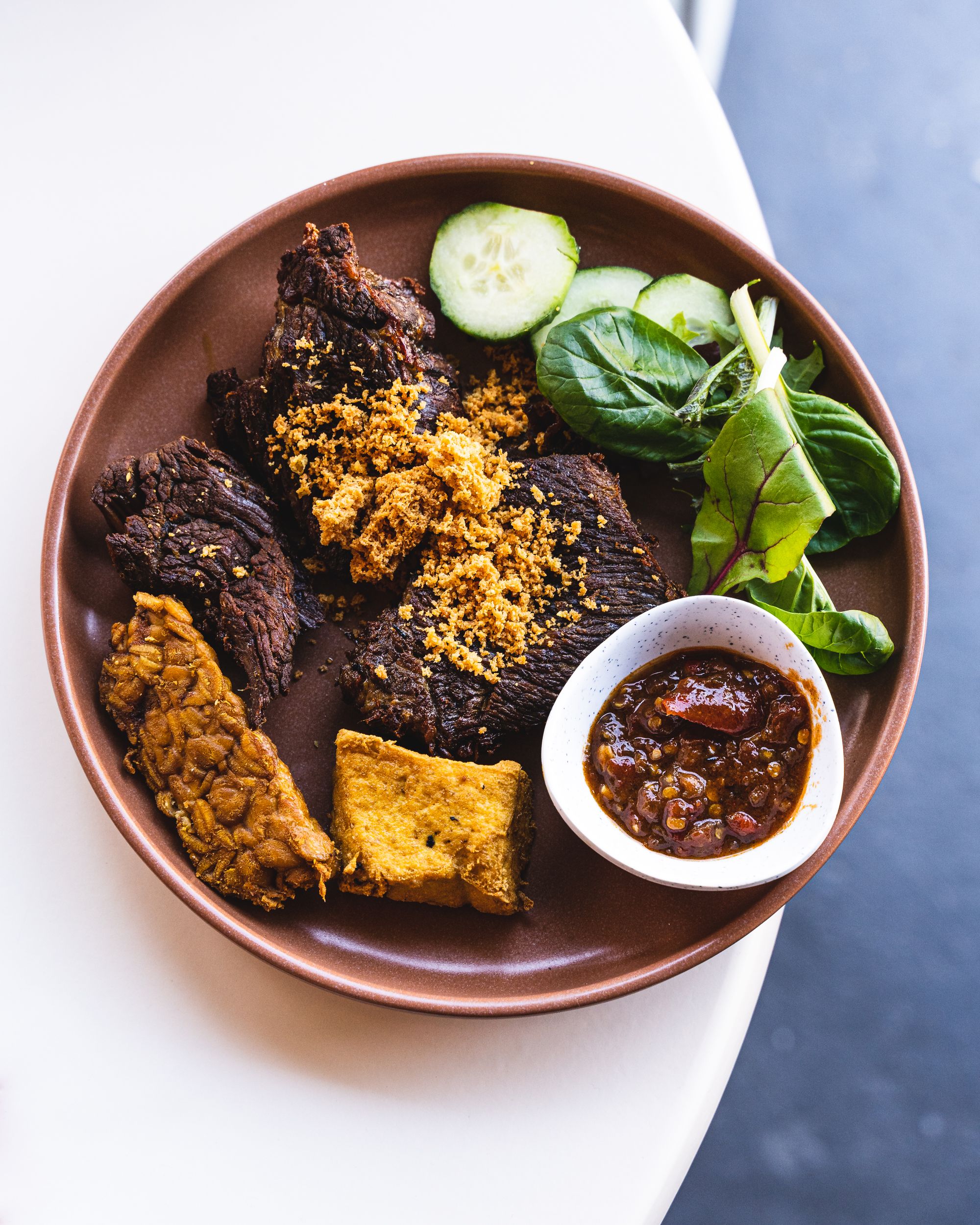 Top down shot of fried beef steak with tempeh and sambal