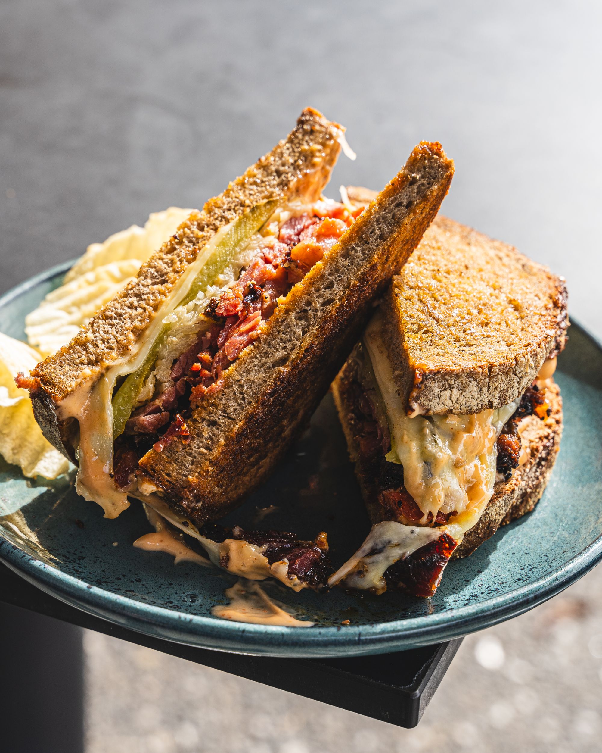 Close up of Reuben sandwich with smoked pastrami, cheese, bread and crisps