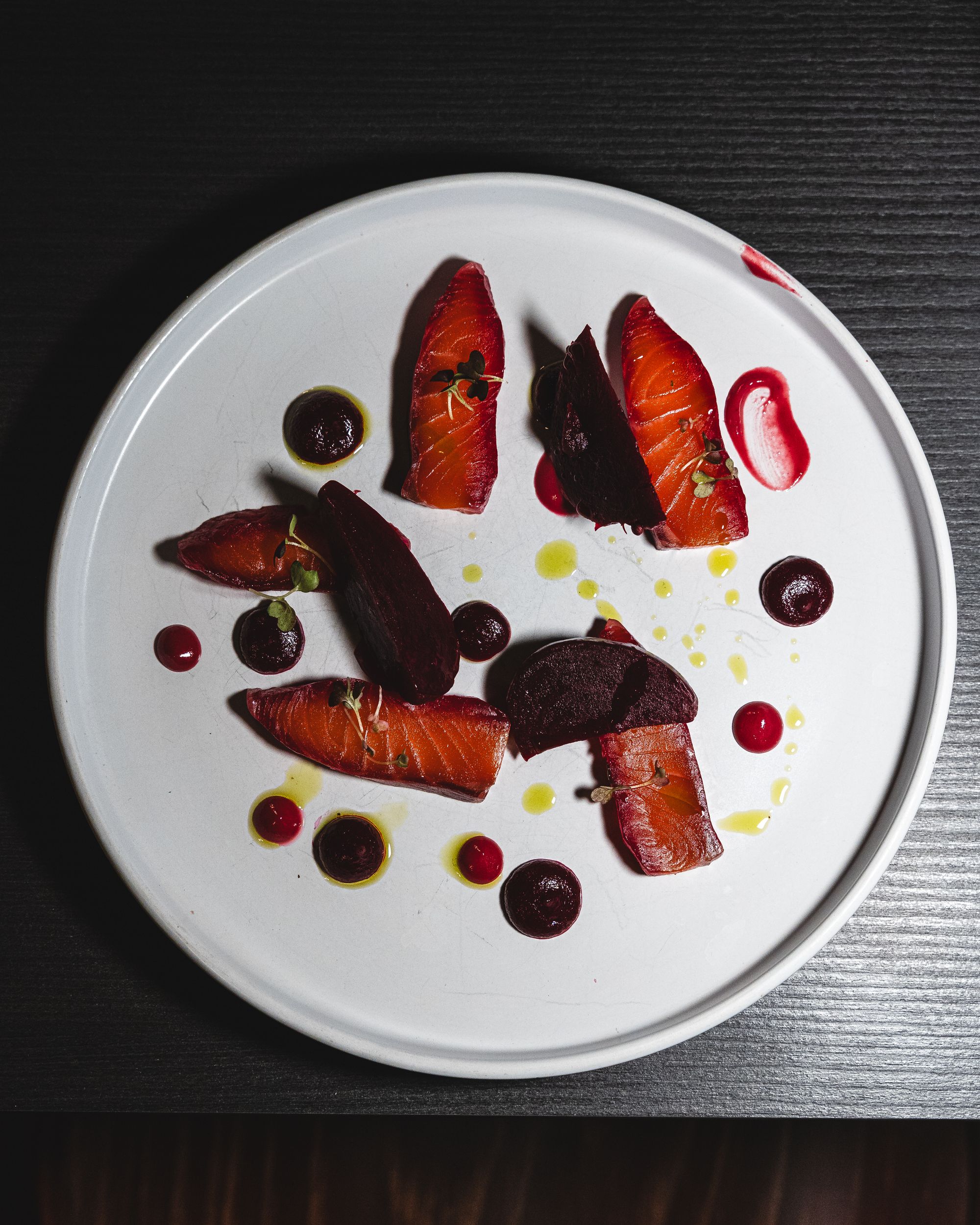 Top down shot of cured salmon artistically plated with beetroot and horseradish gel