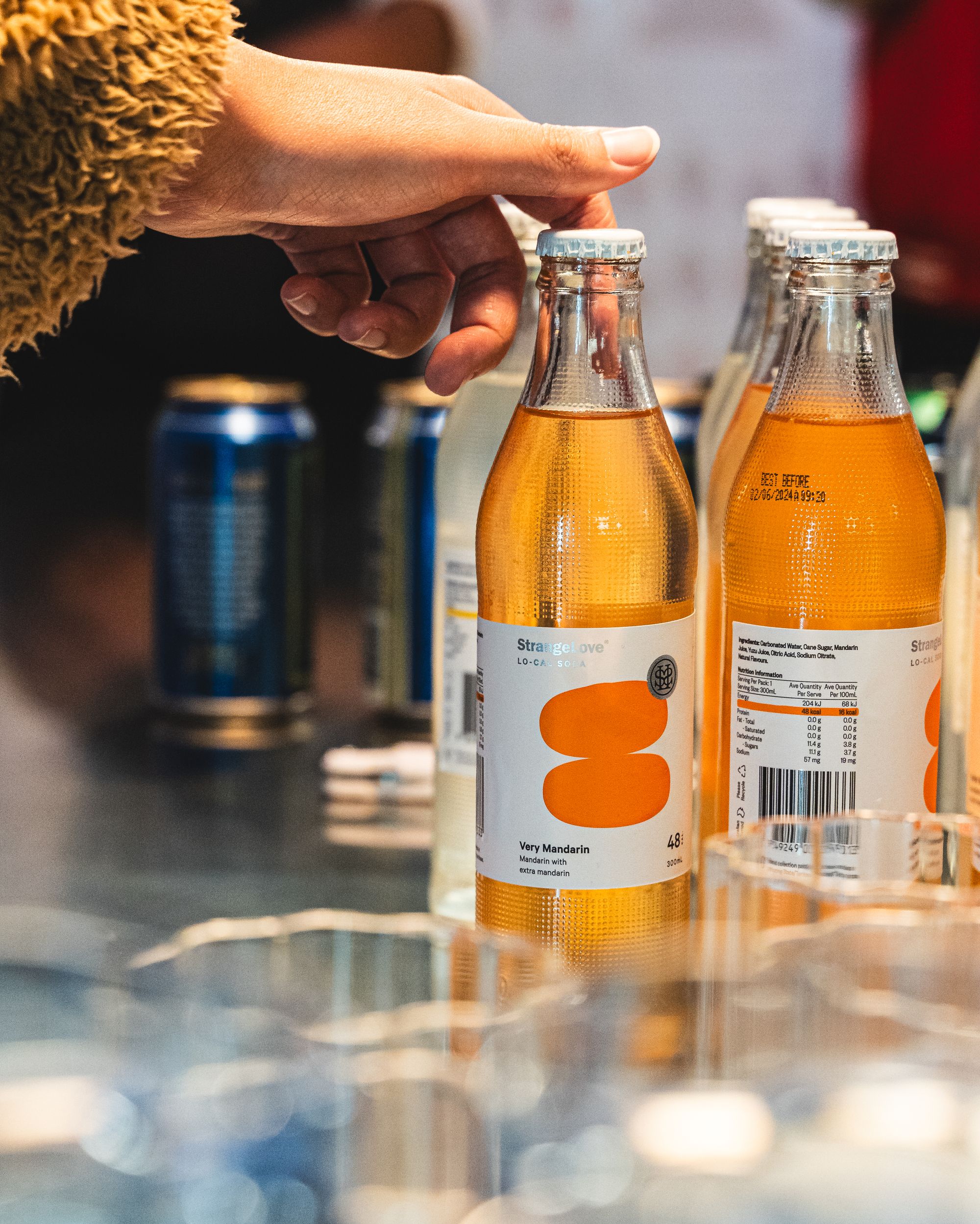 Hand picking up a bottle of fruit soda