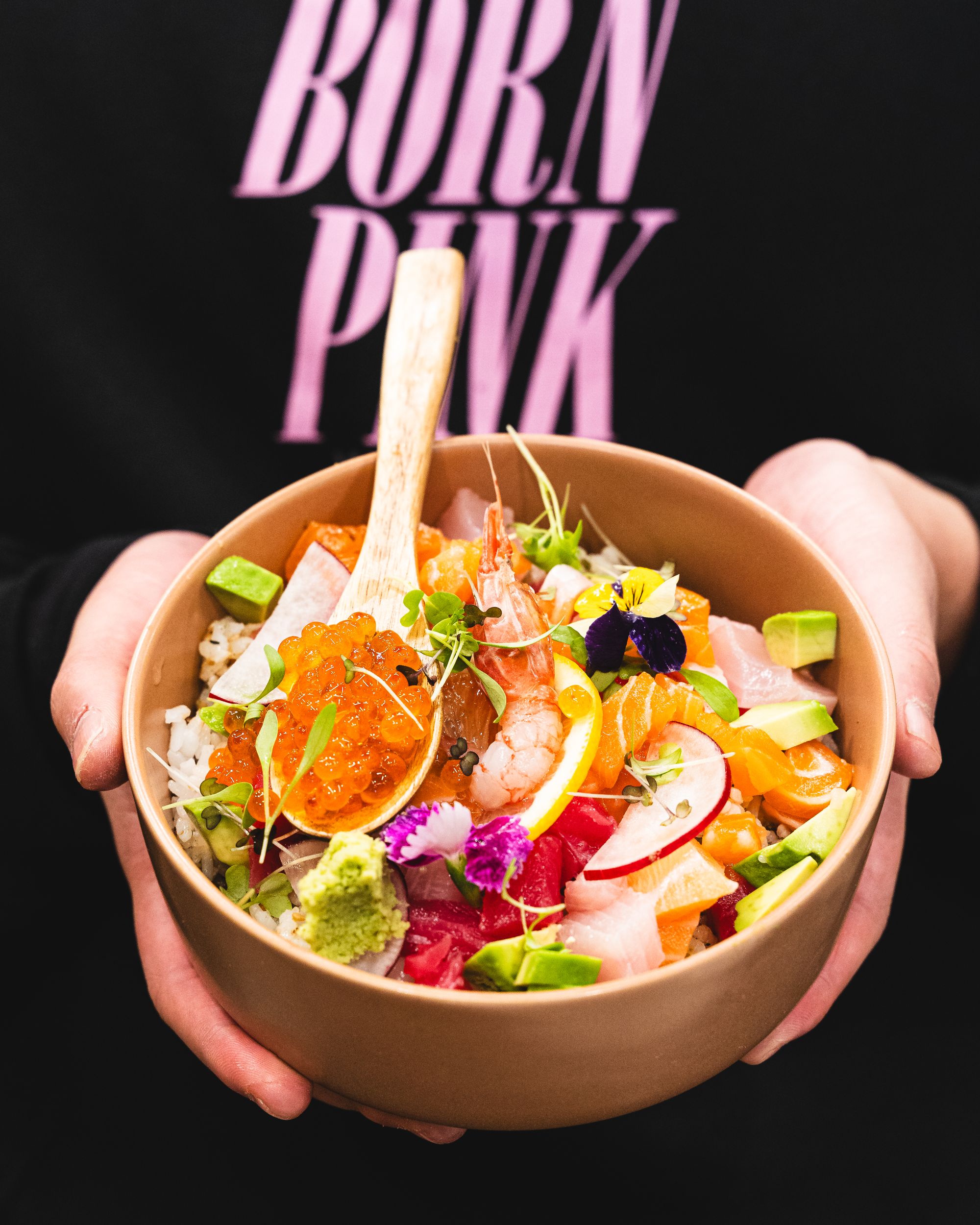 Hand holding bowl with diced sashimi (ikura, amaebi, salmon, tuna and yellowtail)