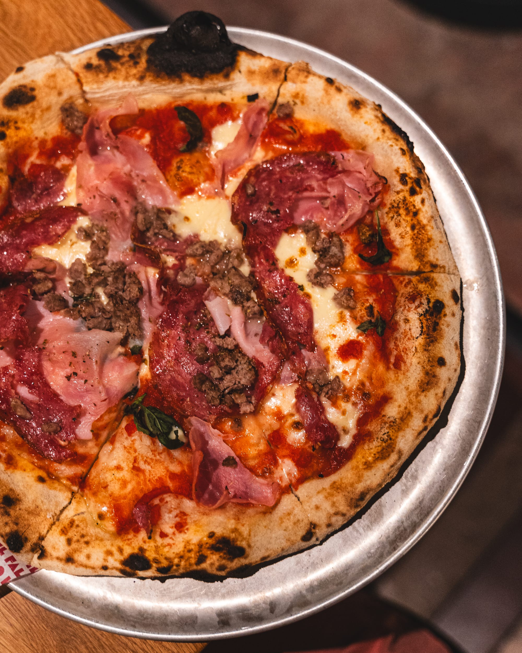 Top down shot of pizza with cheese, ham,, mushroom, olives and herbs