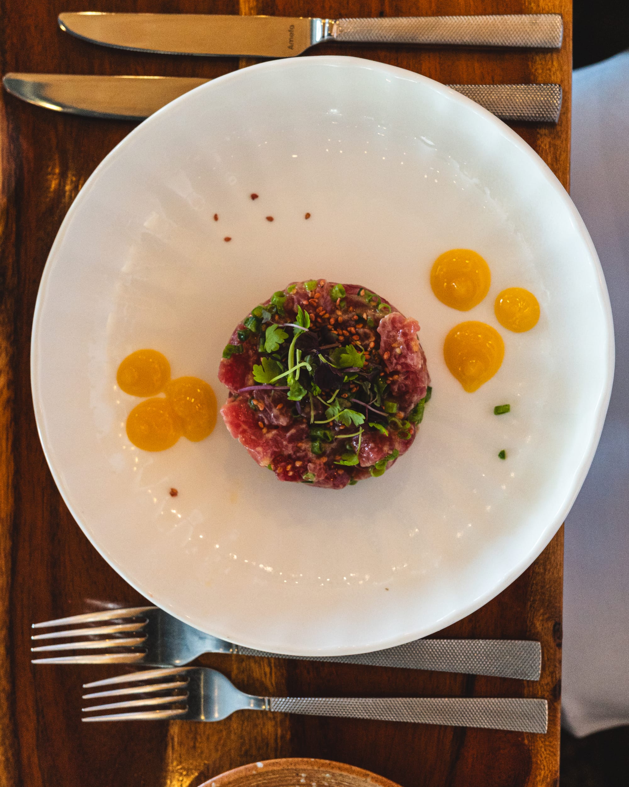 Top down shot of a circular tuna tartare with citrus gels