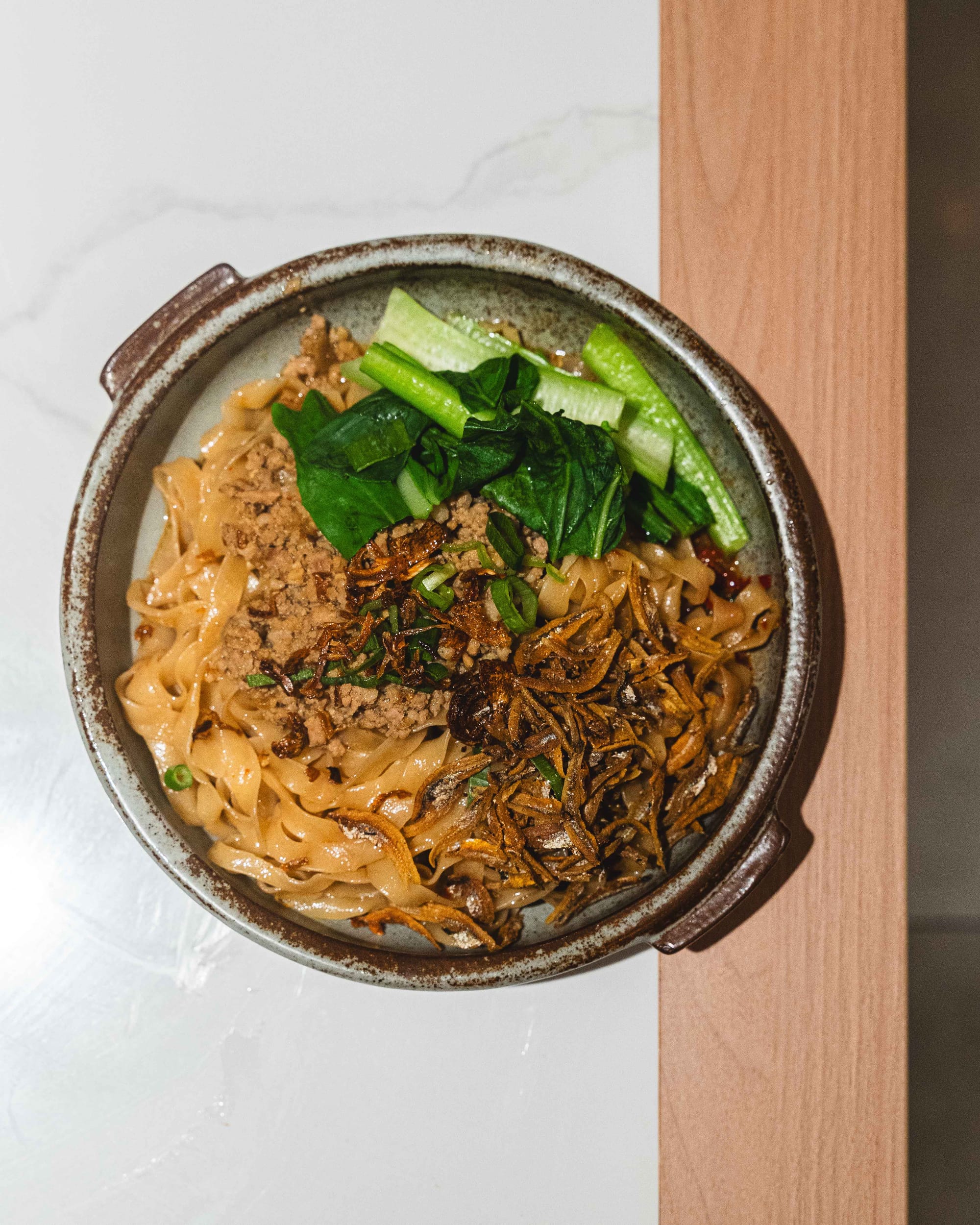 Top down of chilli pan mee with anchovies, bok choy and noodles