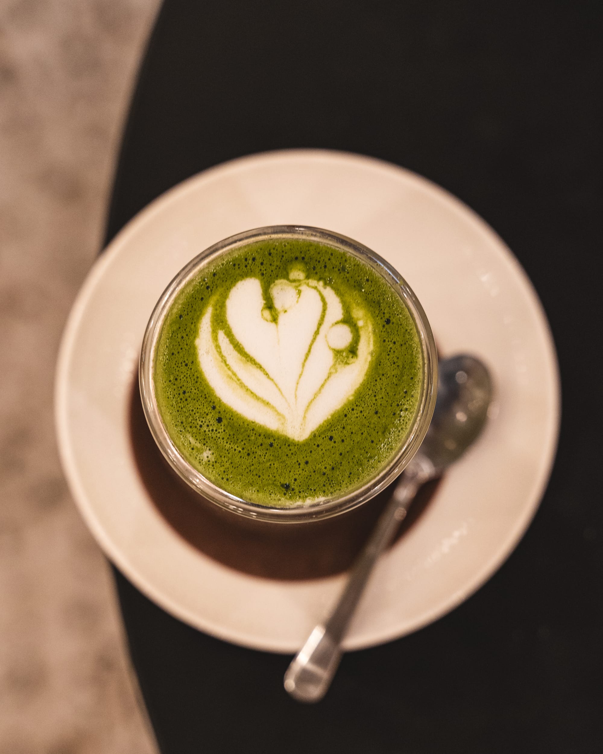 Top down shot of matcha latte in a glass with a heart latte art