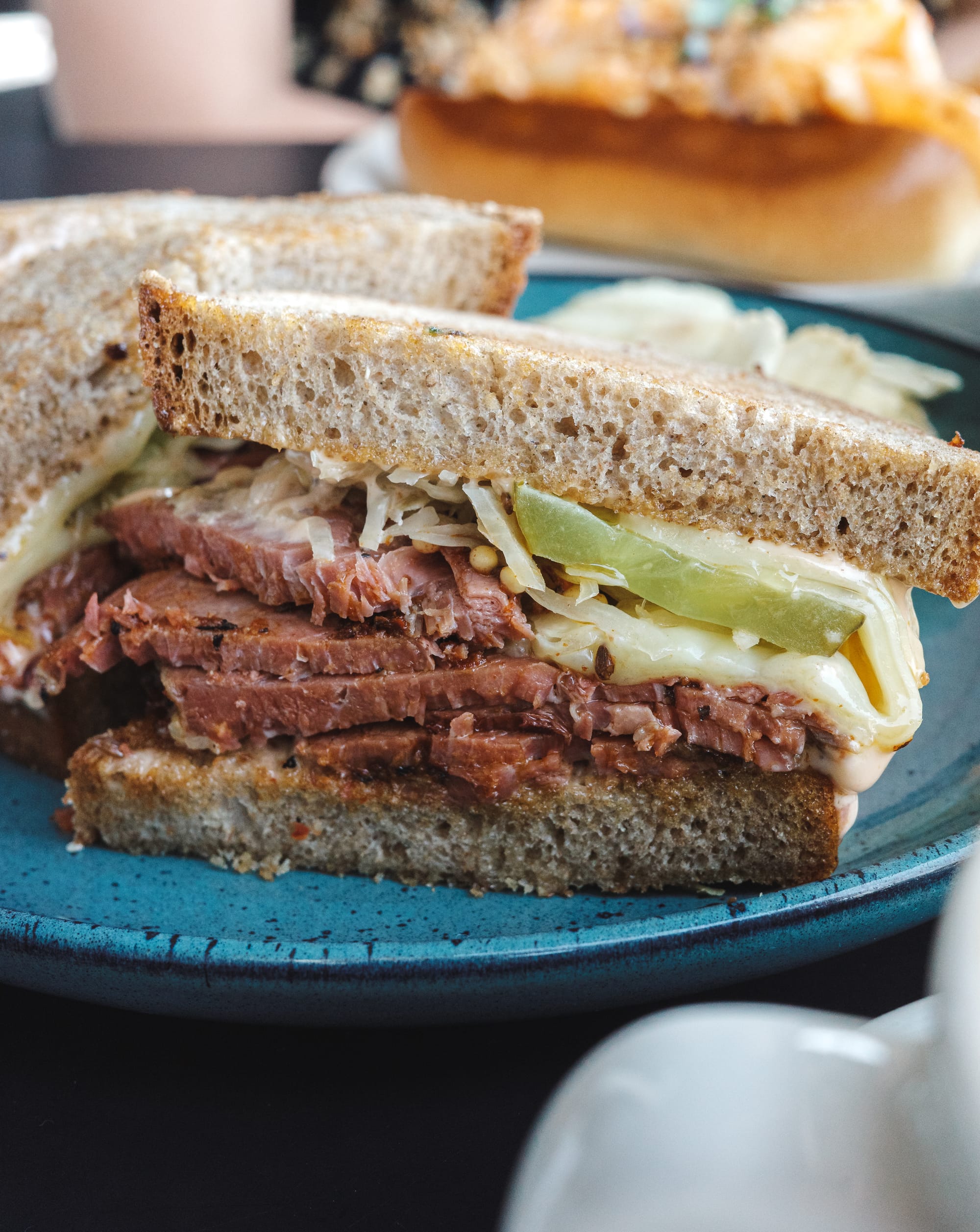 Close up of Reuben sandwich with smoked pastrami, cheese and pickle