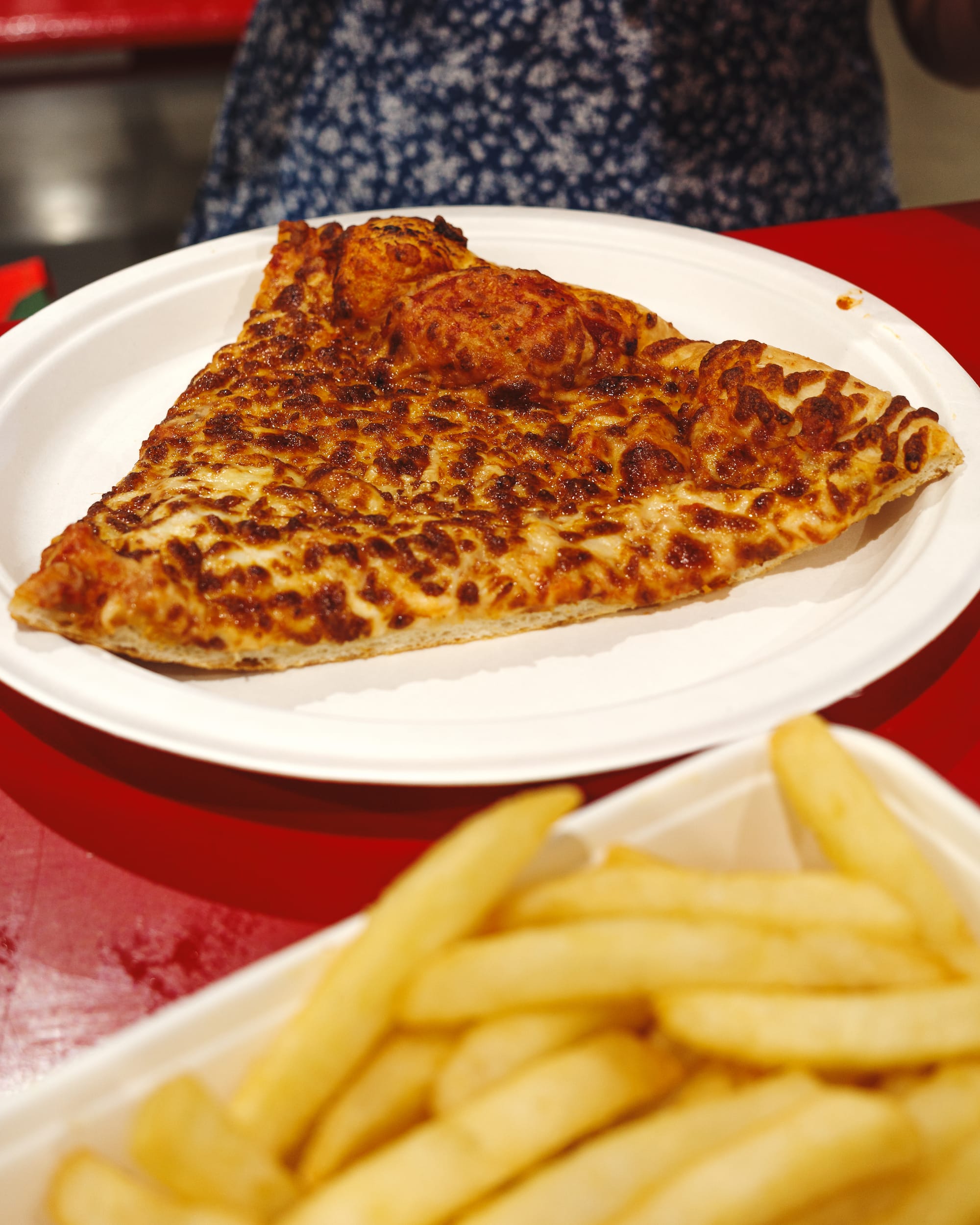 Close up of cheese pizza slice on a paper plate