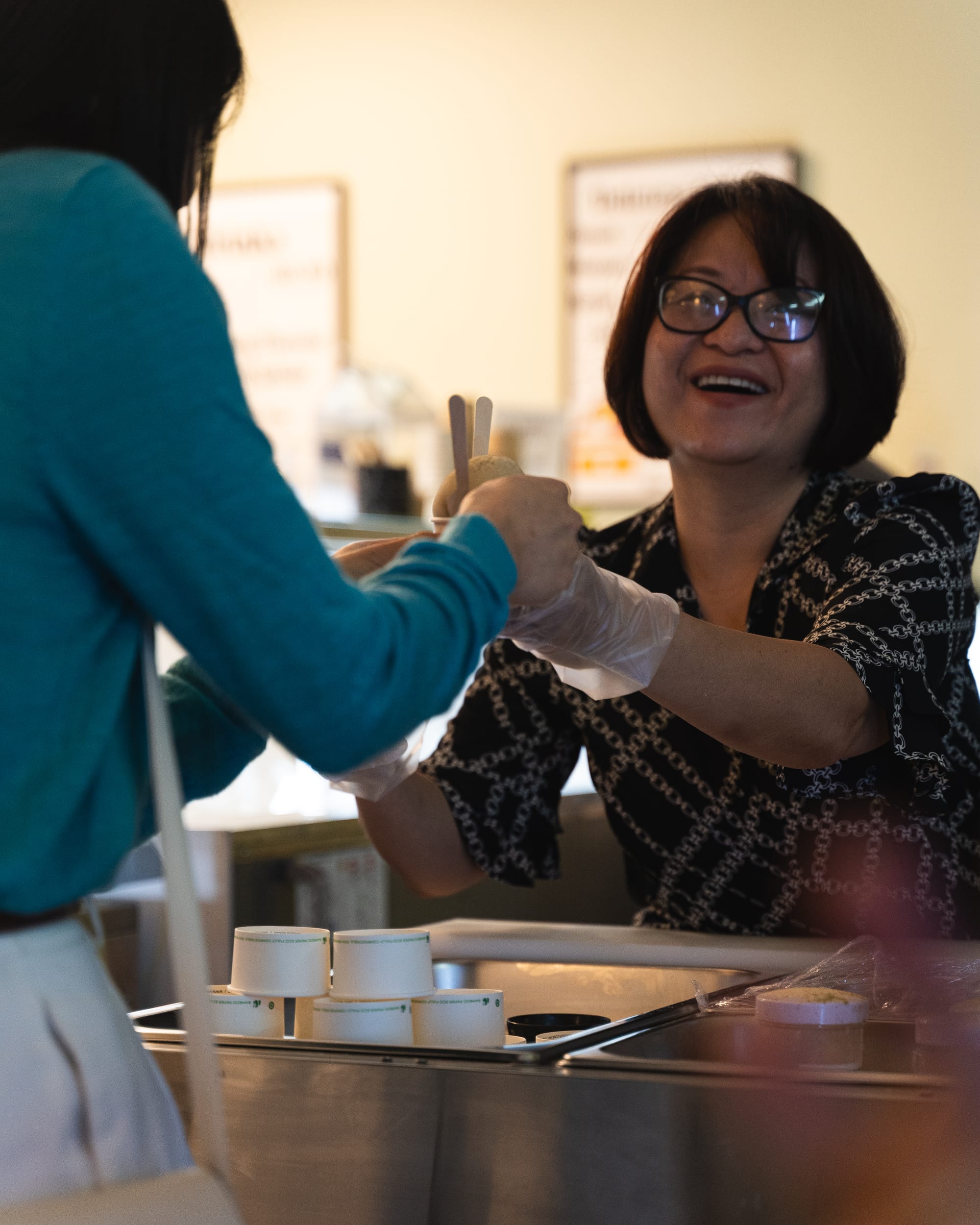 Photo of smiling lady handing a customer a dessert