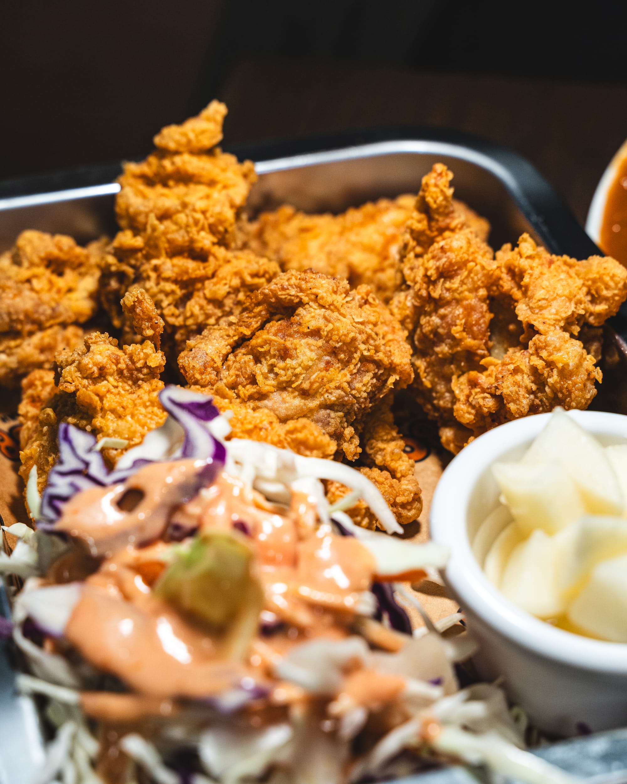 Close up of fried chicken with salad and pickled radish in the foreground