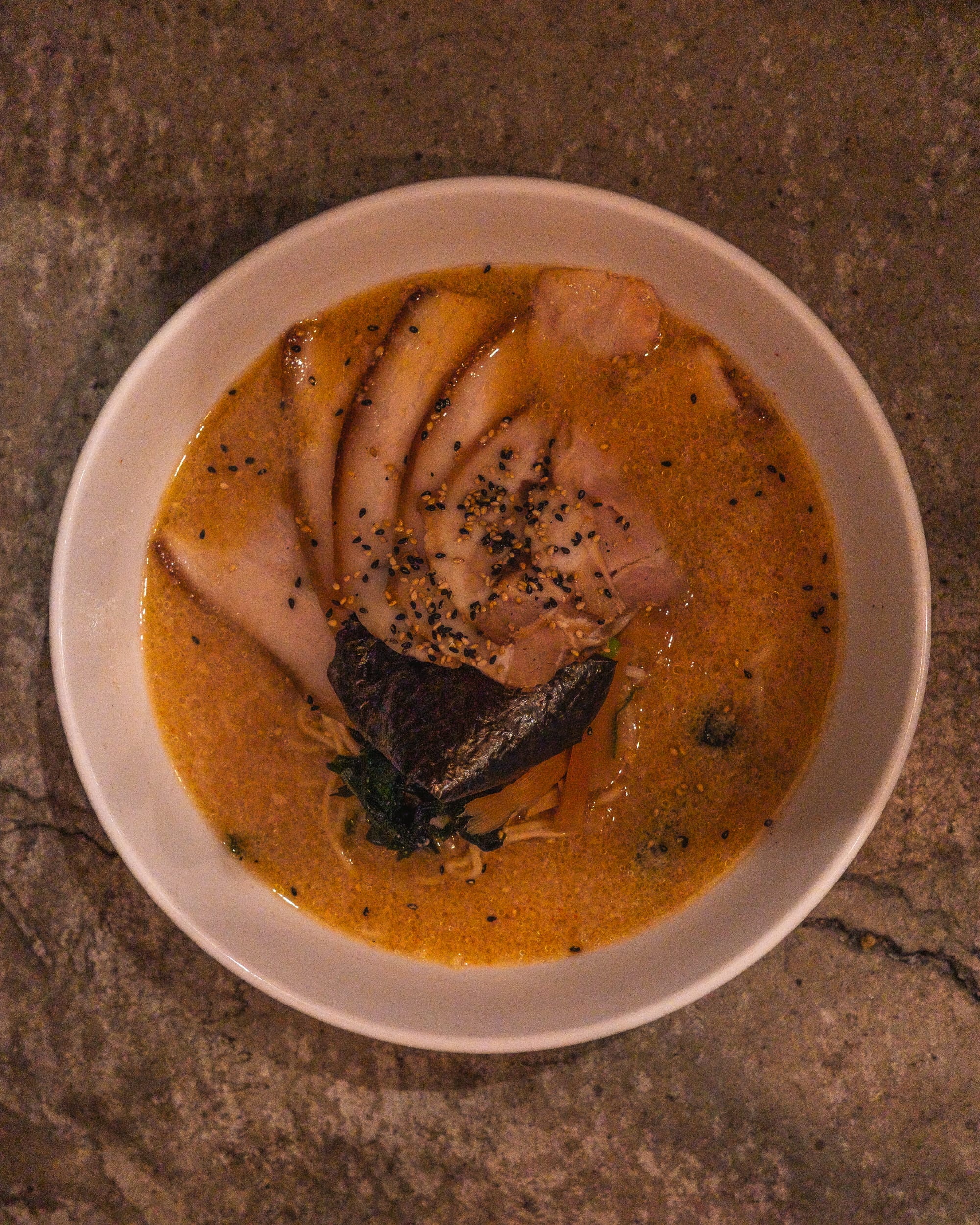 Top down close up shot of ramen with chashu, seasame seeds and ramen noodles