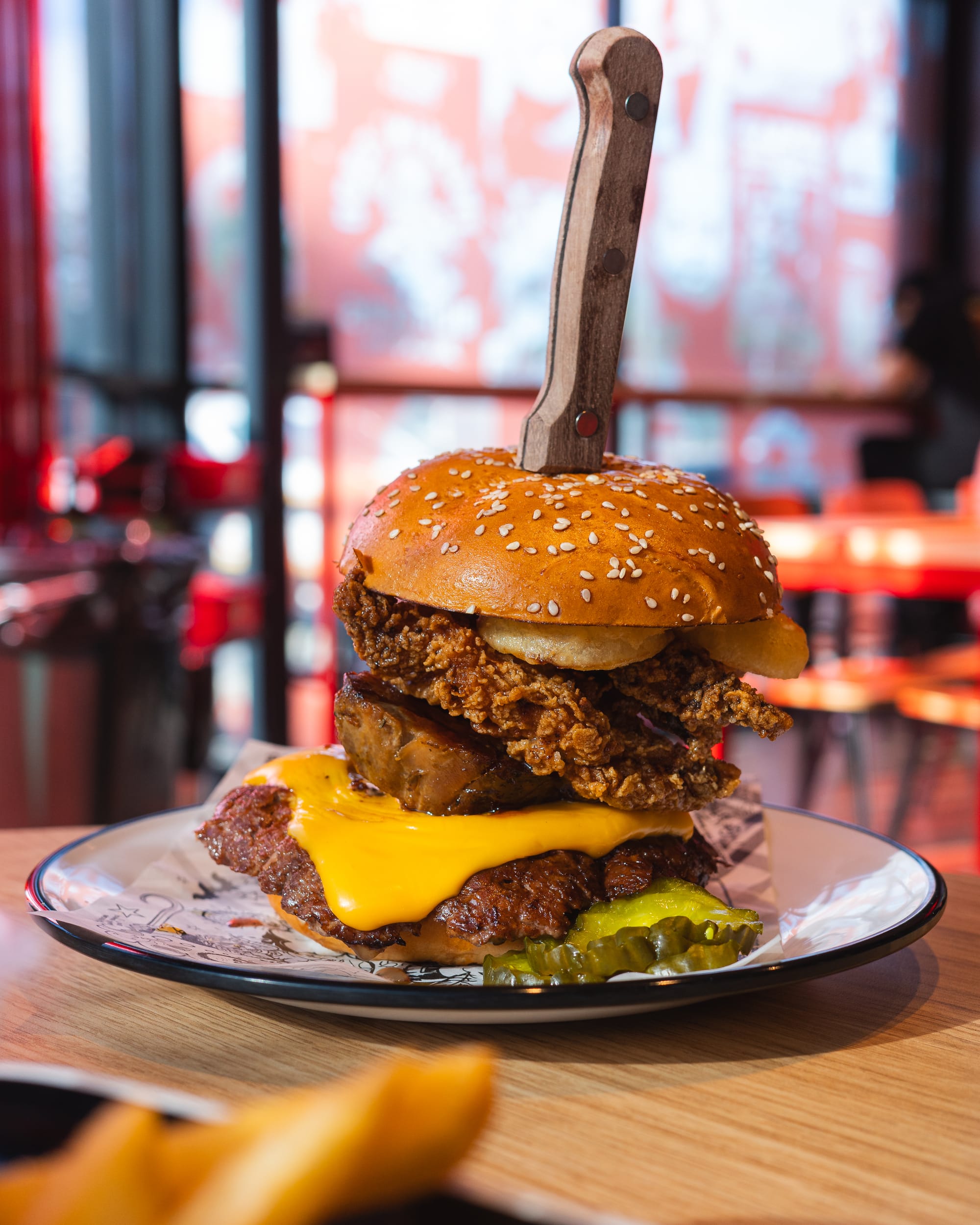 Close up of burger cross section showing pickles, beef patty, pork belly, fried chicken