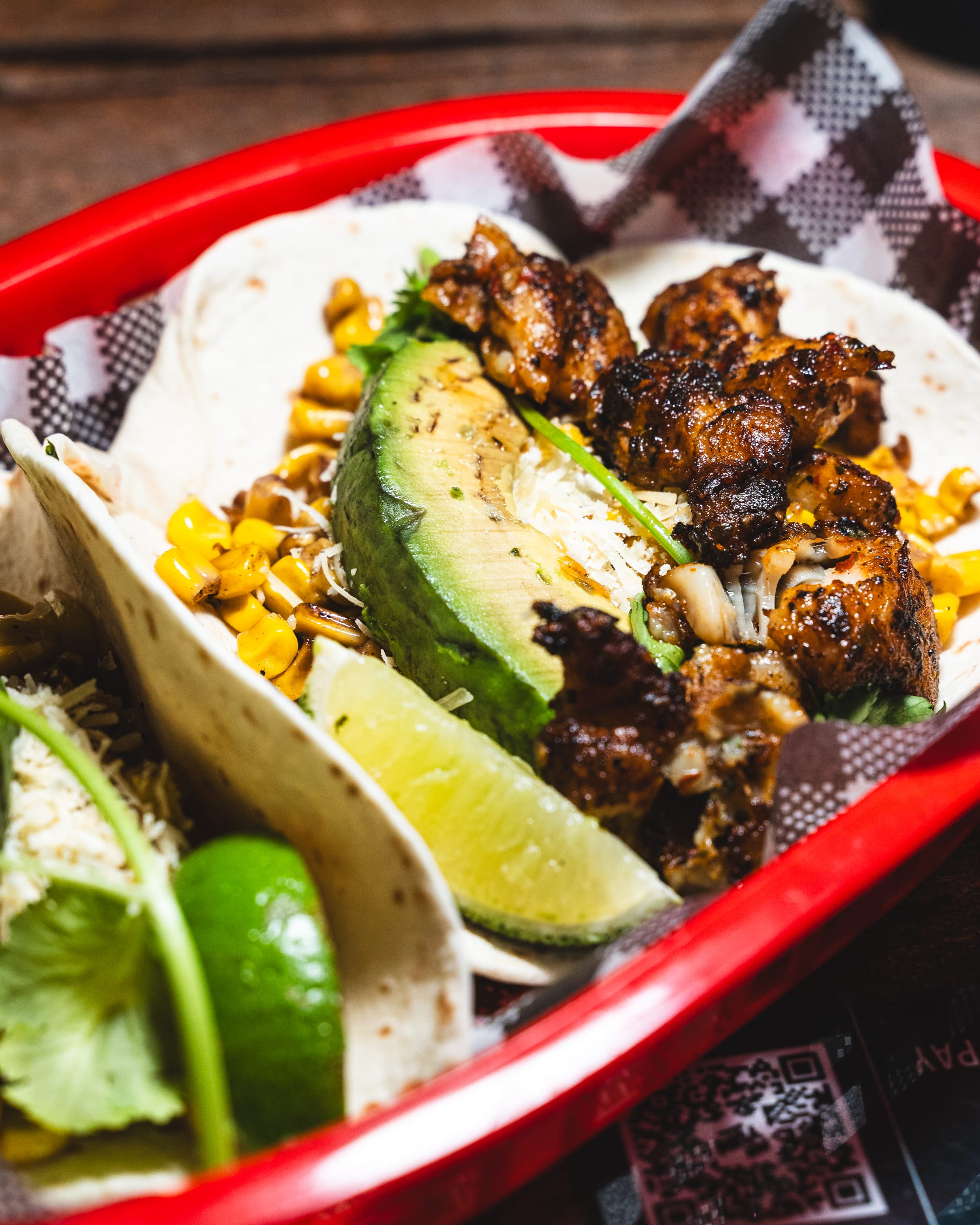 Close up of fish tacos with avocado, corn and lime showing