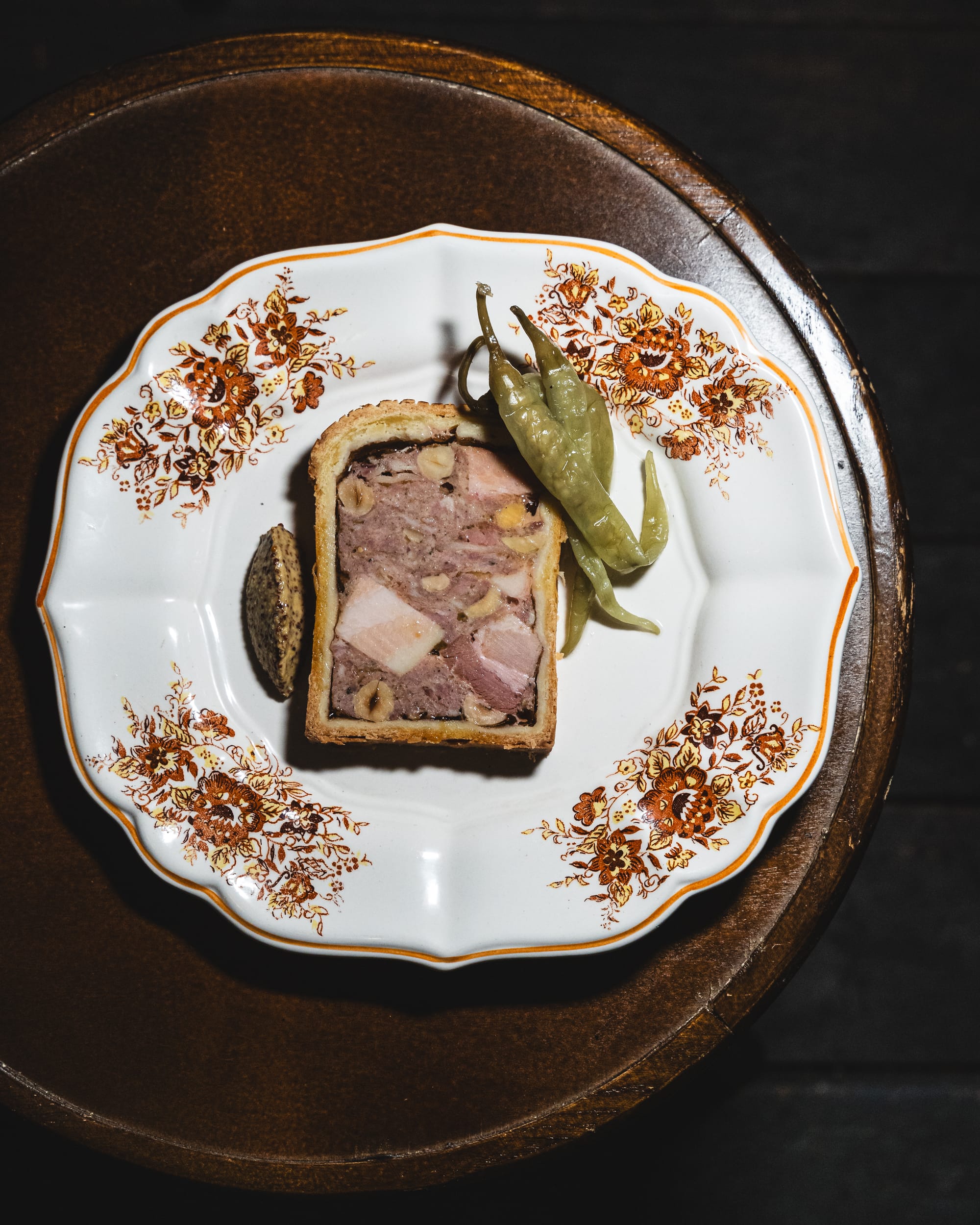 Top down shot of pate en croute with chilli pepper and a quinnell of mustard