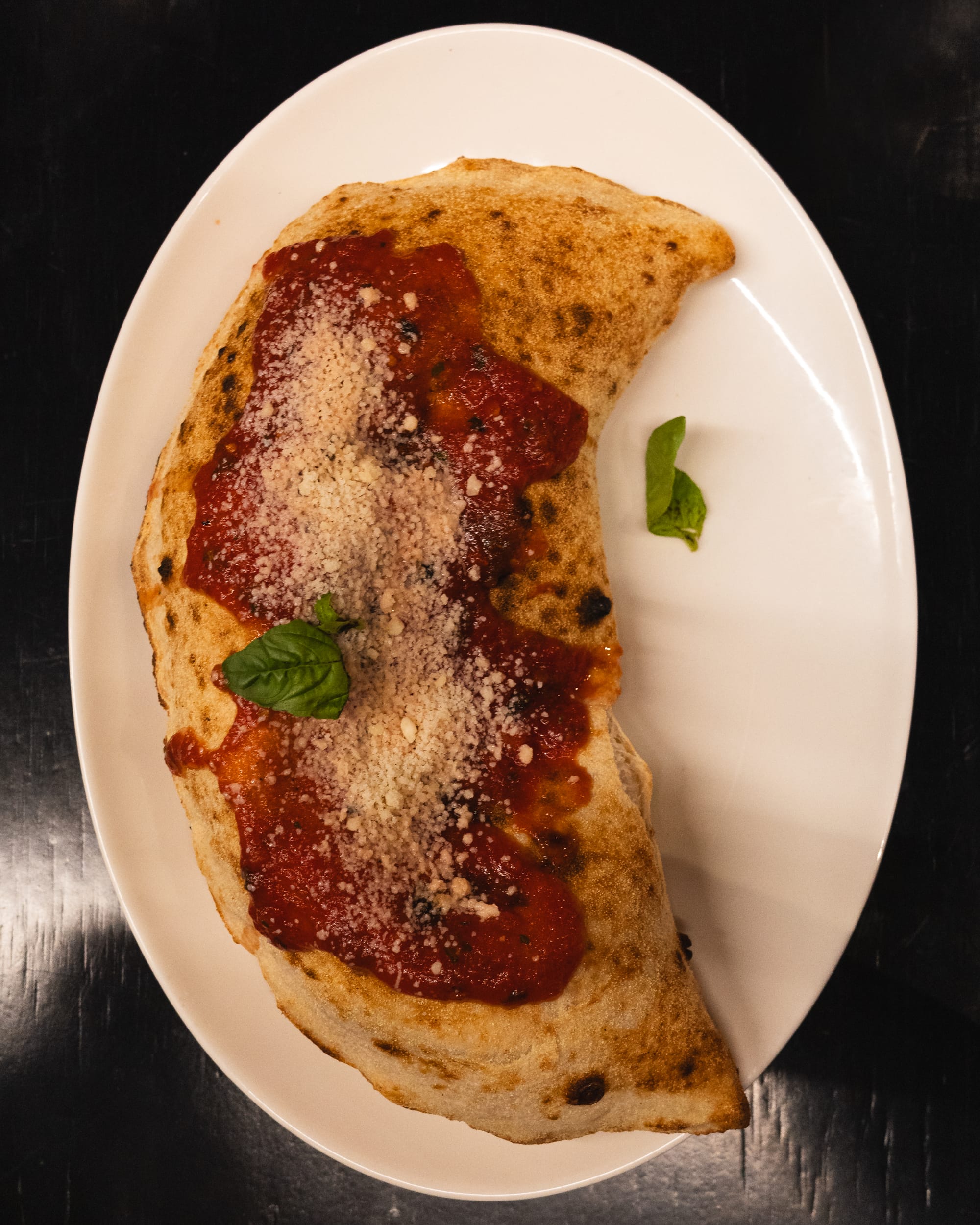 Top down shot of calzone topped with basil and cheese