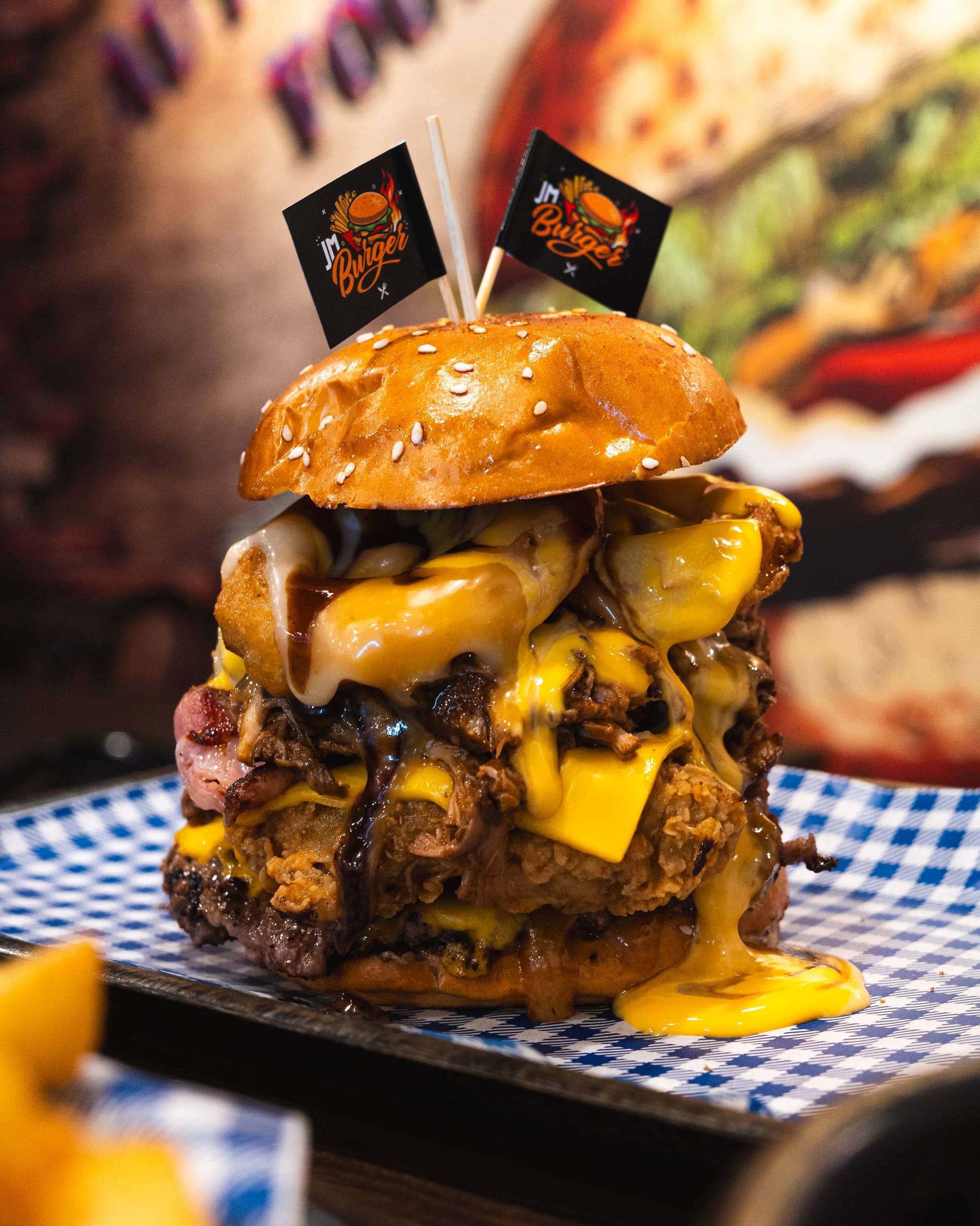 Close up of burger with melted cheese, bacon, fried chicken and a beef patty