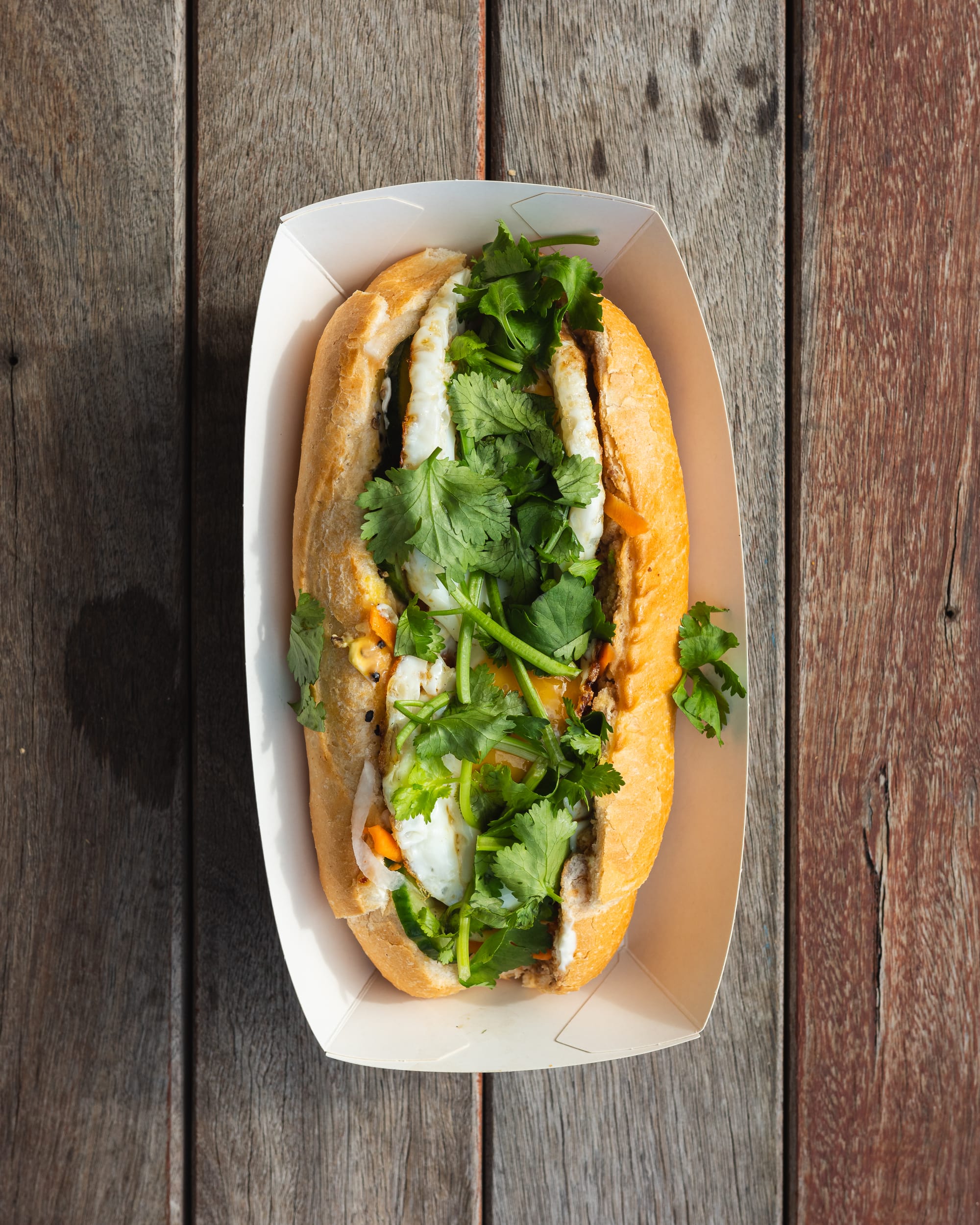 Top down shot of banh mi with egg, coriander and pickled carrots showing