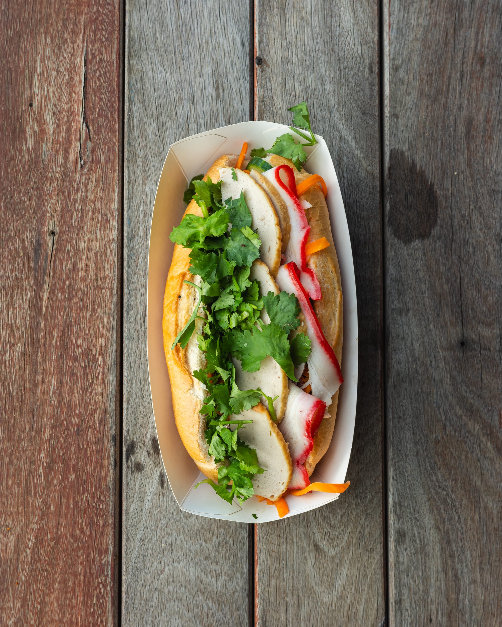 Top down shot of banh mi with Vietnamese ham, coriander and pickled carrot showing