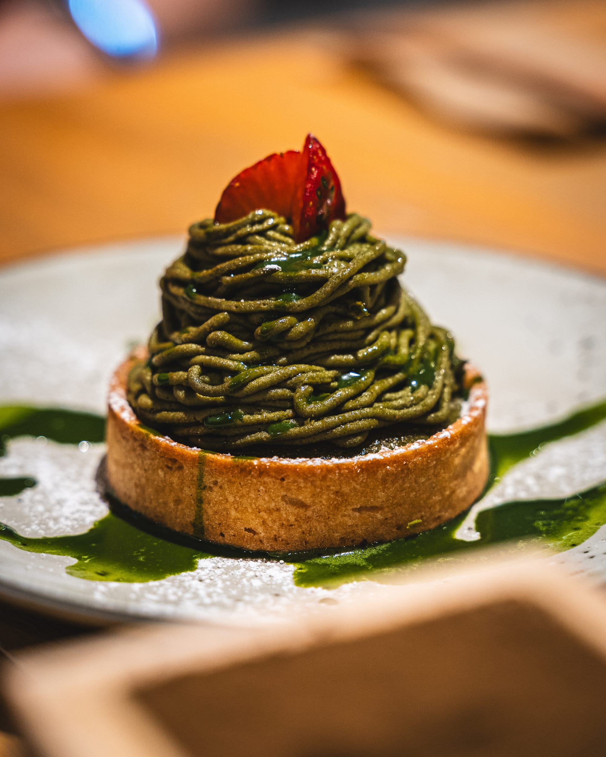 A matcha Mont Blanc tart with delicate green tea cream piped on top, garnished with a strawberry.