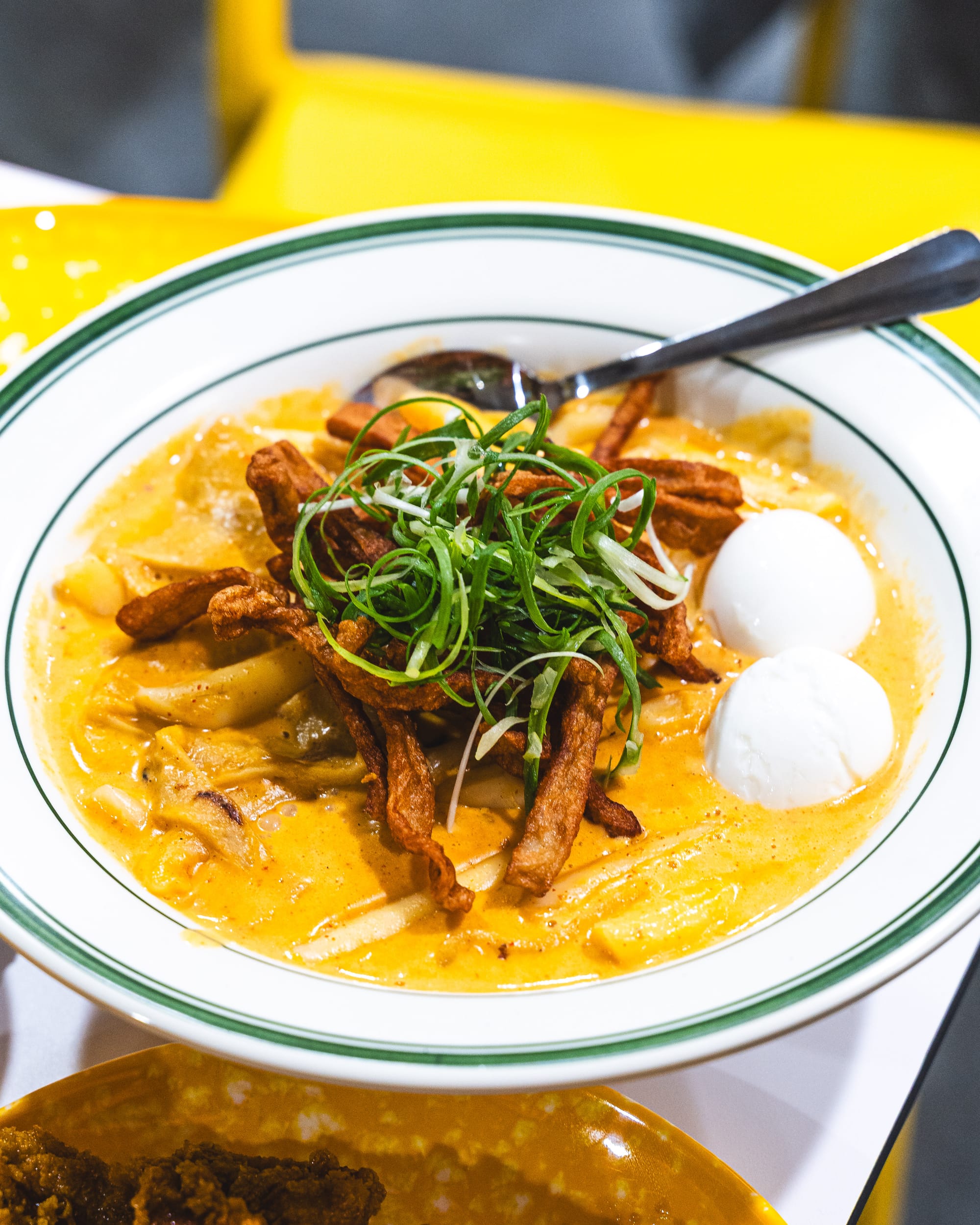 Close up of rose tteokbokki with soft boiled eggs and spring onions