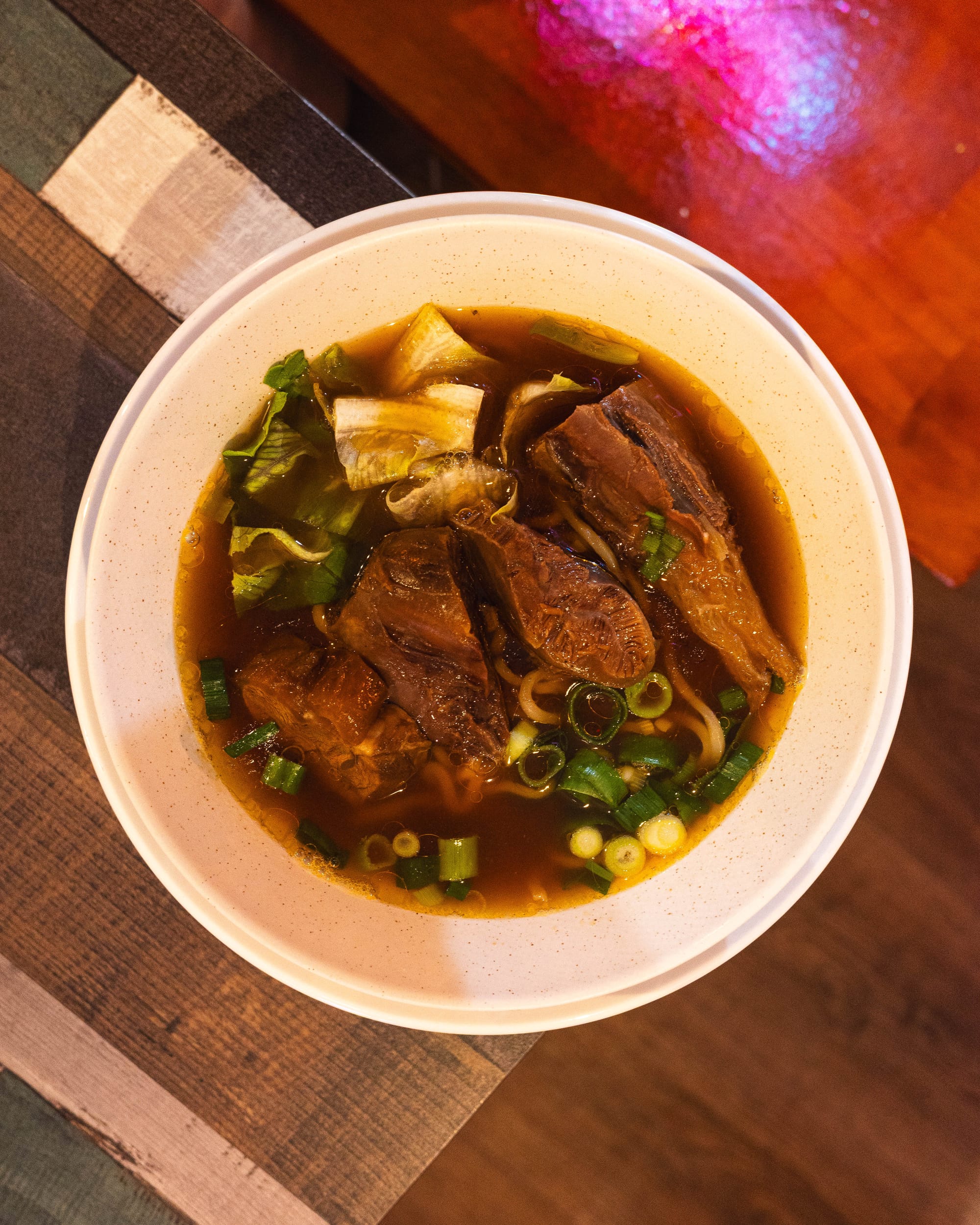 Top down shot of beef noodles with spring onions and beef brisket and vegetables